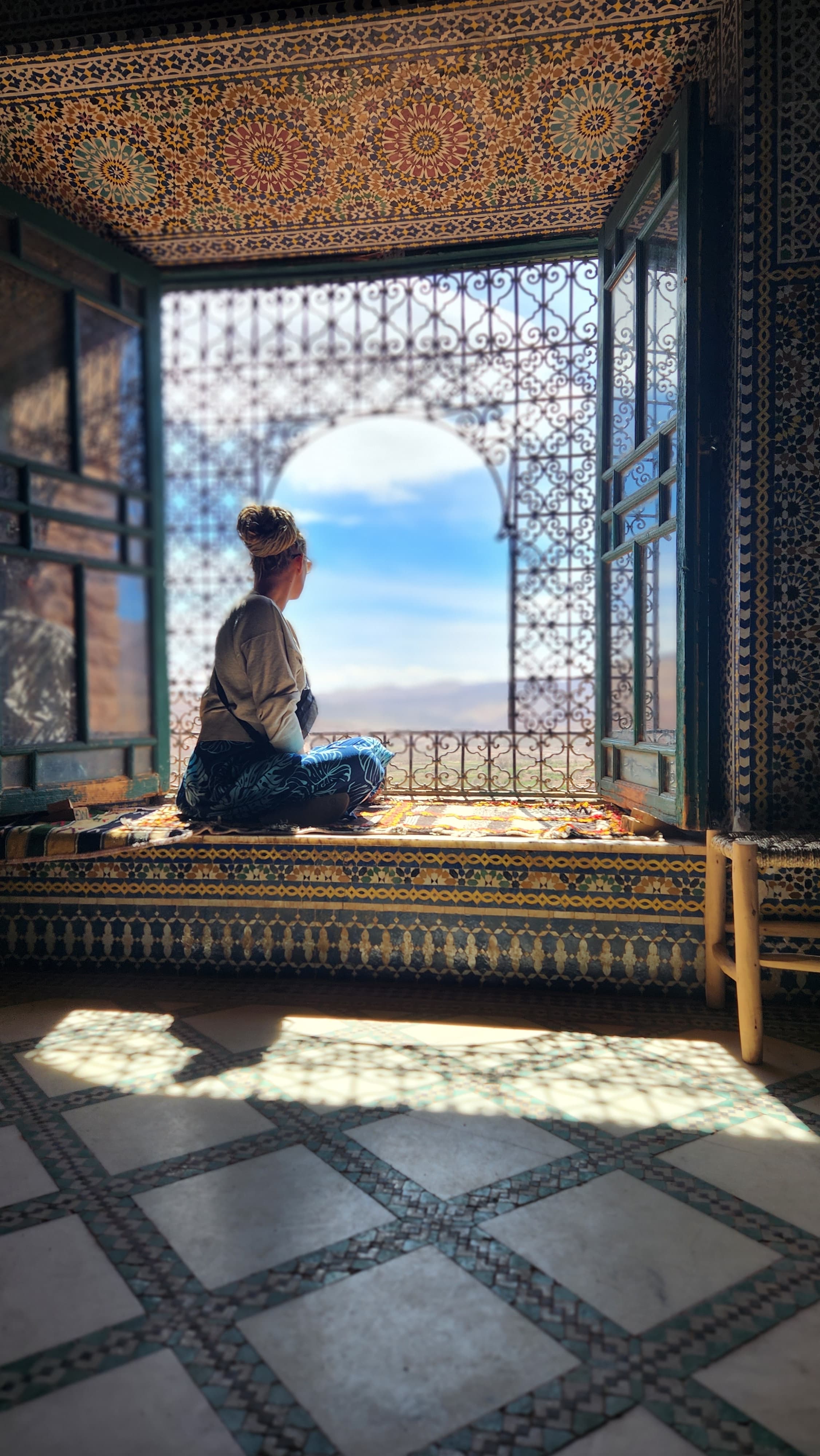 A woman staring out of a beautiful windowsill with tile detailing in the surrounding area.