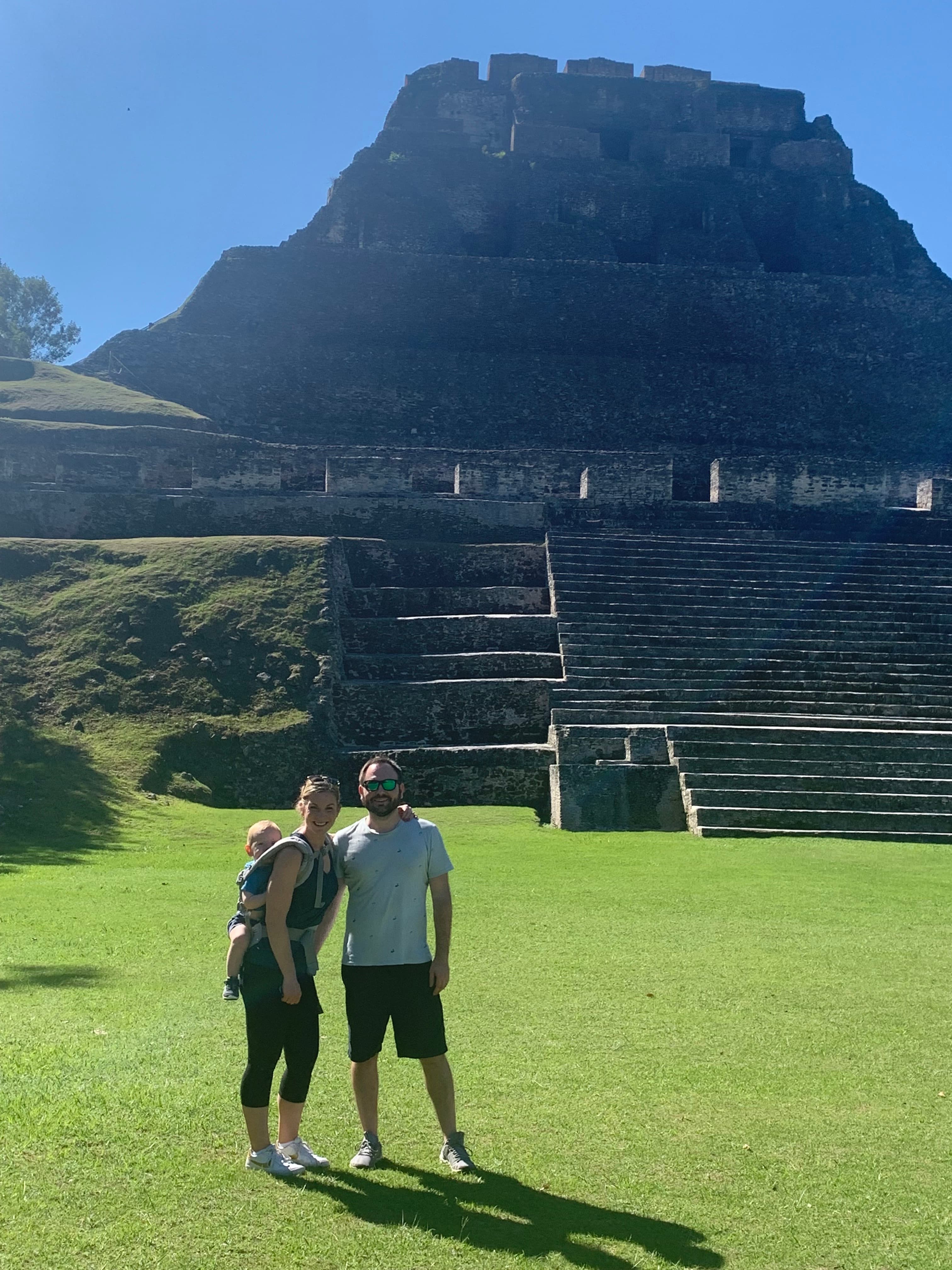 Two people posing in front of an ancient pyramid during the daytime.