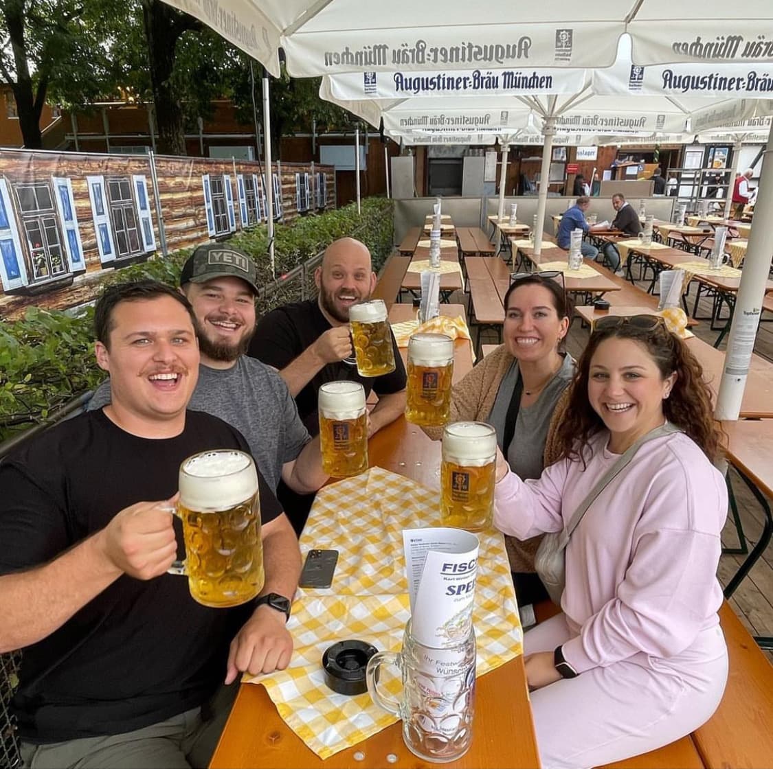 Hannah and friends holding up full steins of beer at a local Oktoberfest at night