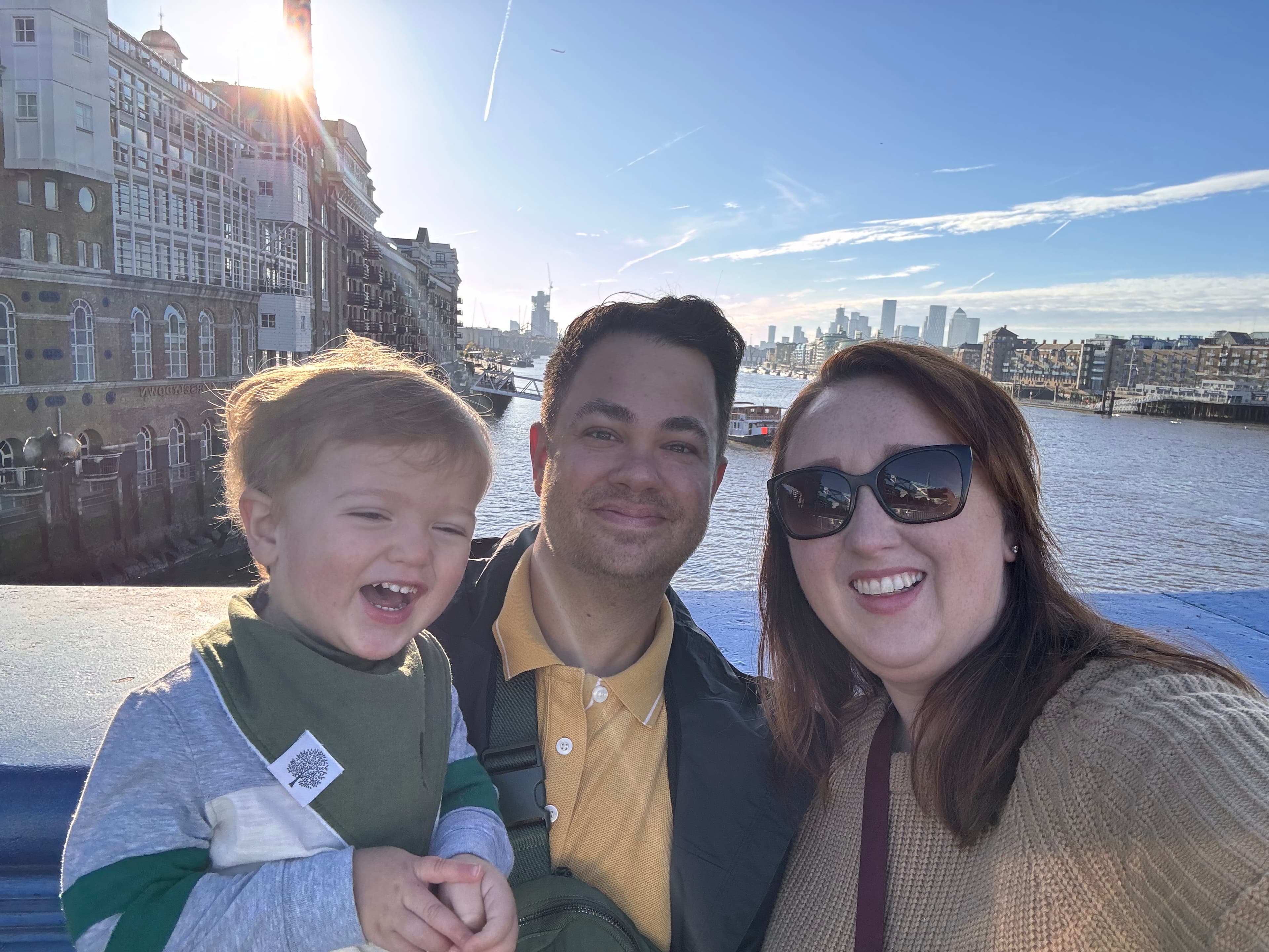 Briana and her family taking a selfie on a bridge overlooking a river with a cityscape behind them