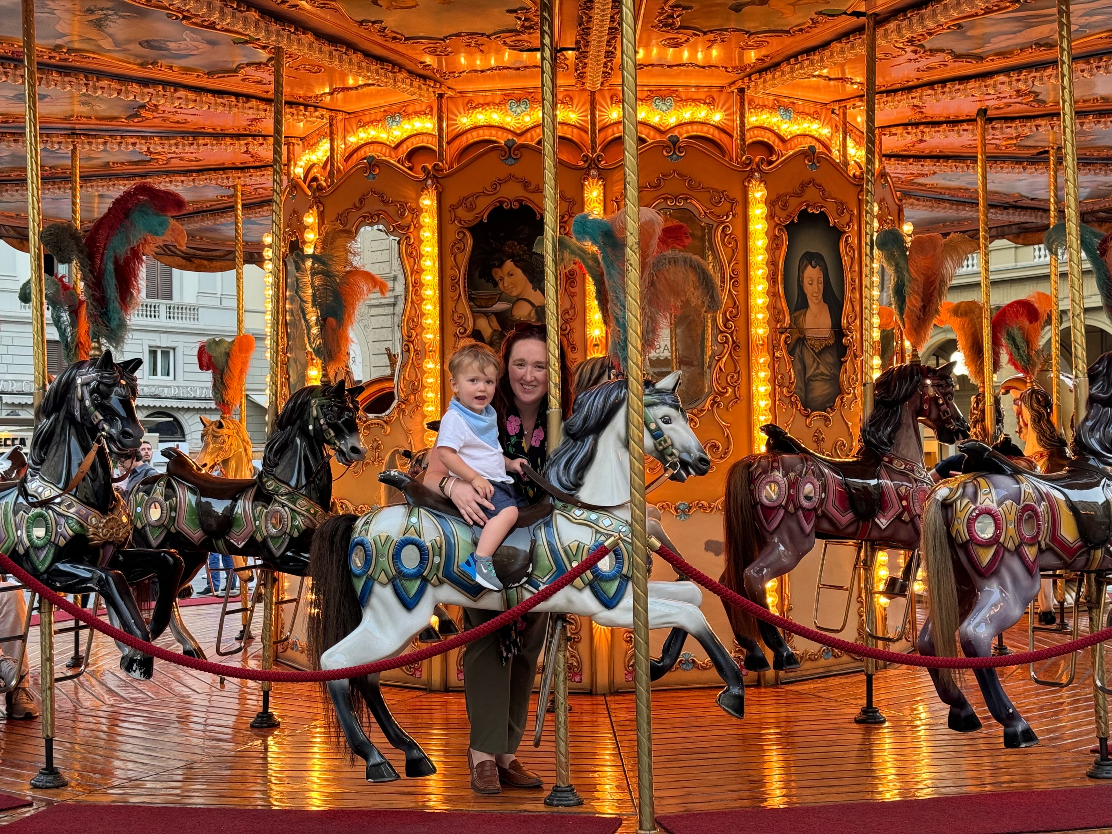 Briana and her child on the horse of a lit up carousel ride