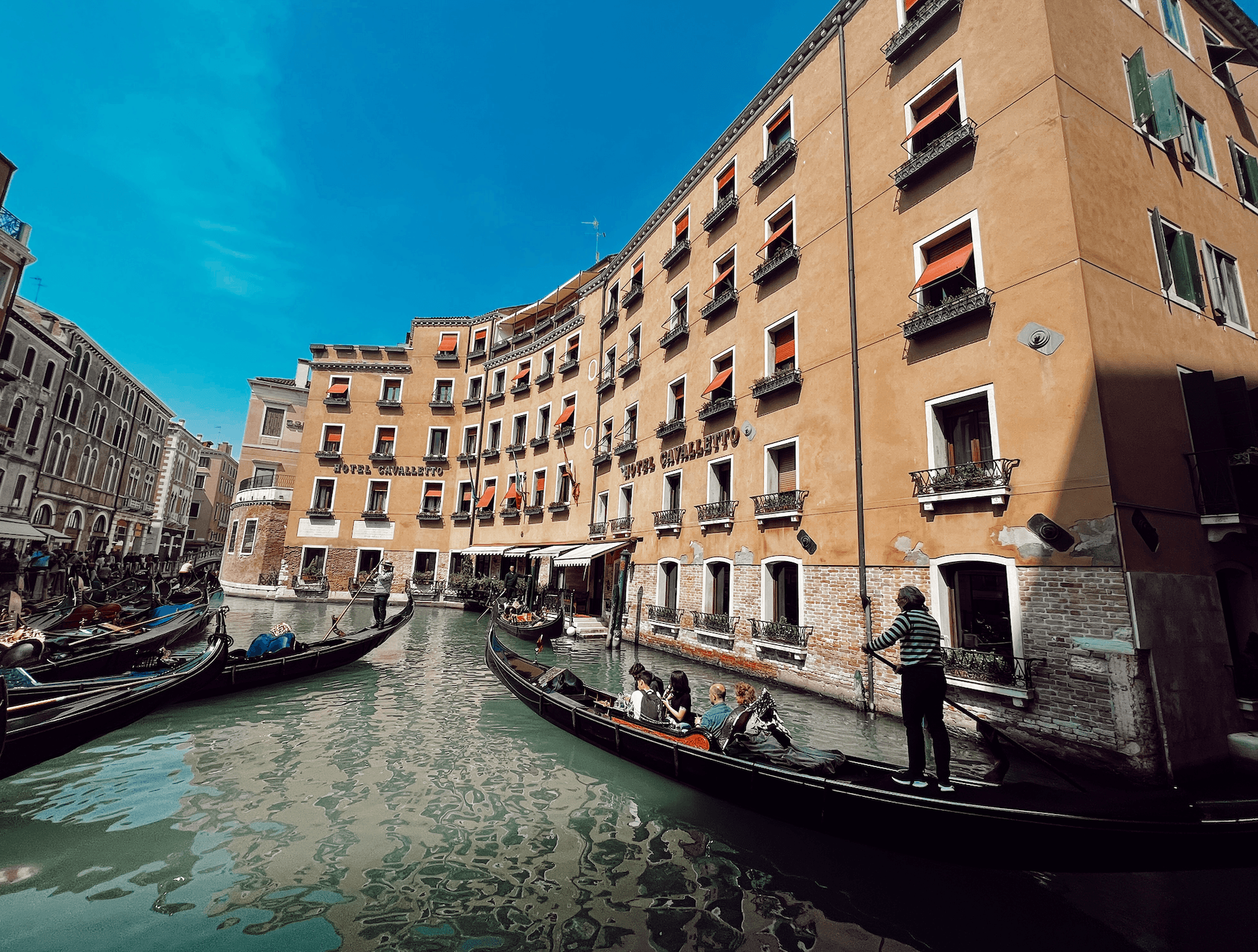 Scenic view of gondolas on canal with buildings in background.