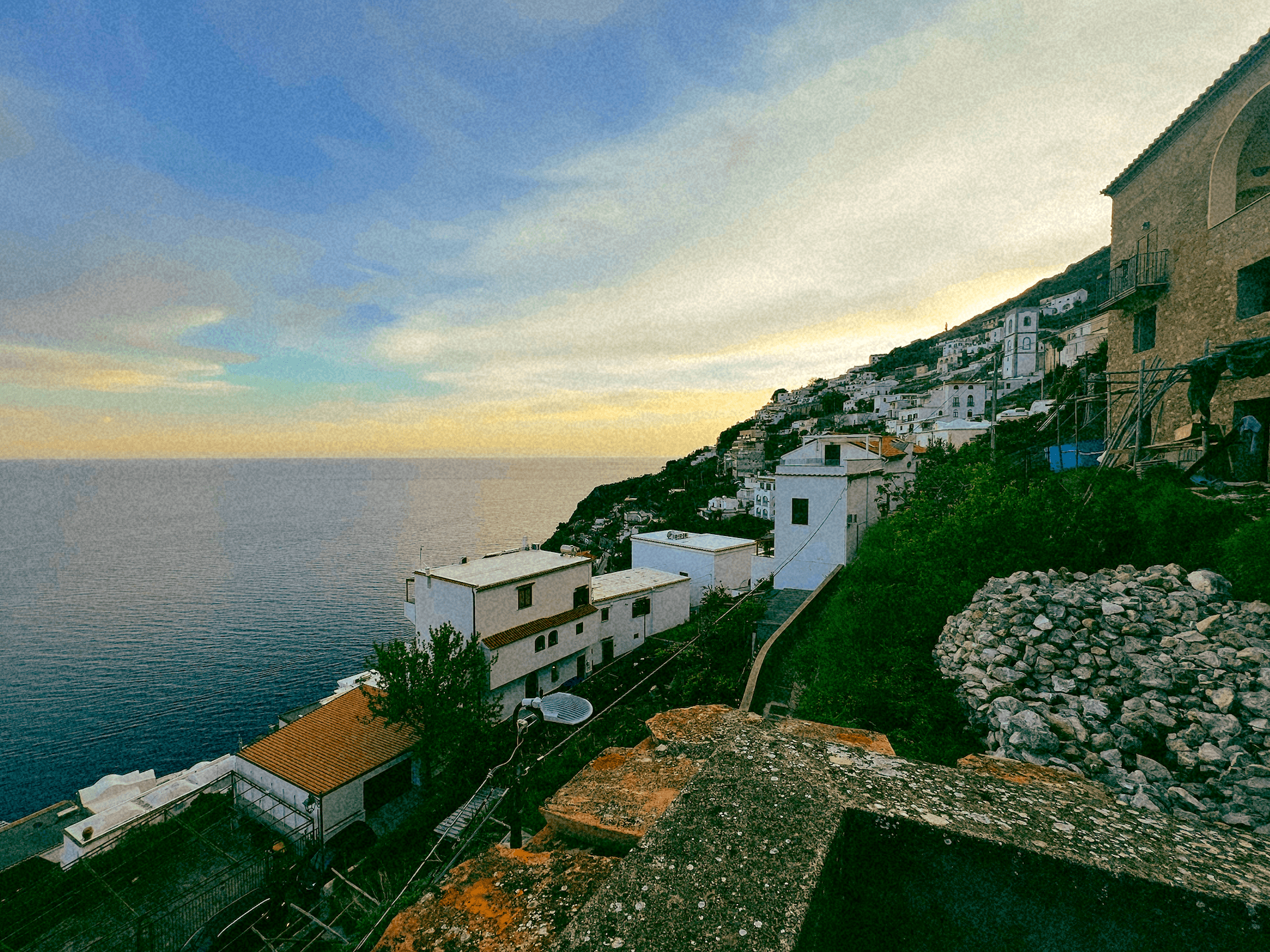 Scenic ocean view from a hilltop, waves crashing on shore, clear blue sky and serene landscape.
