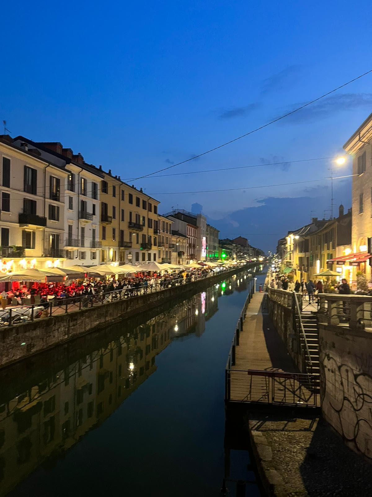 A night view of the town's central canal with illuminated buildings reflecting on the water.