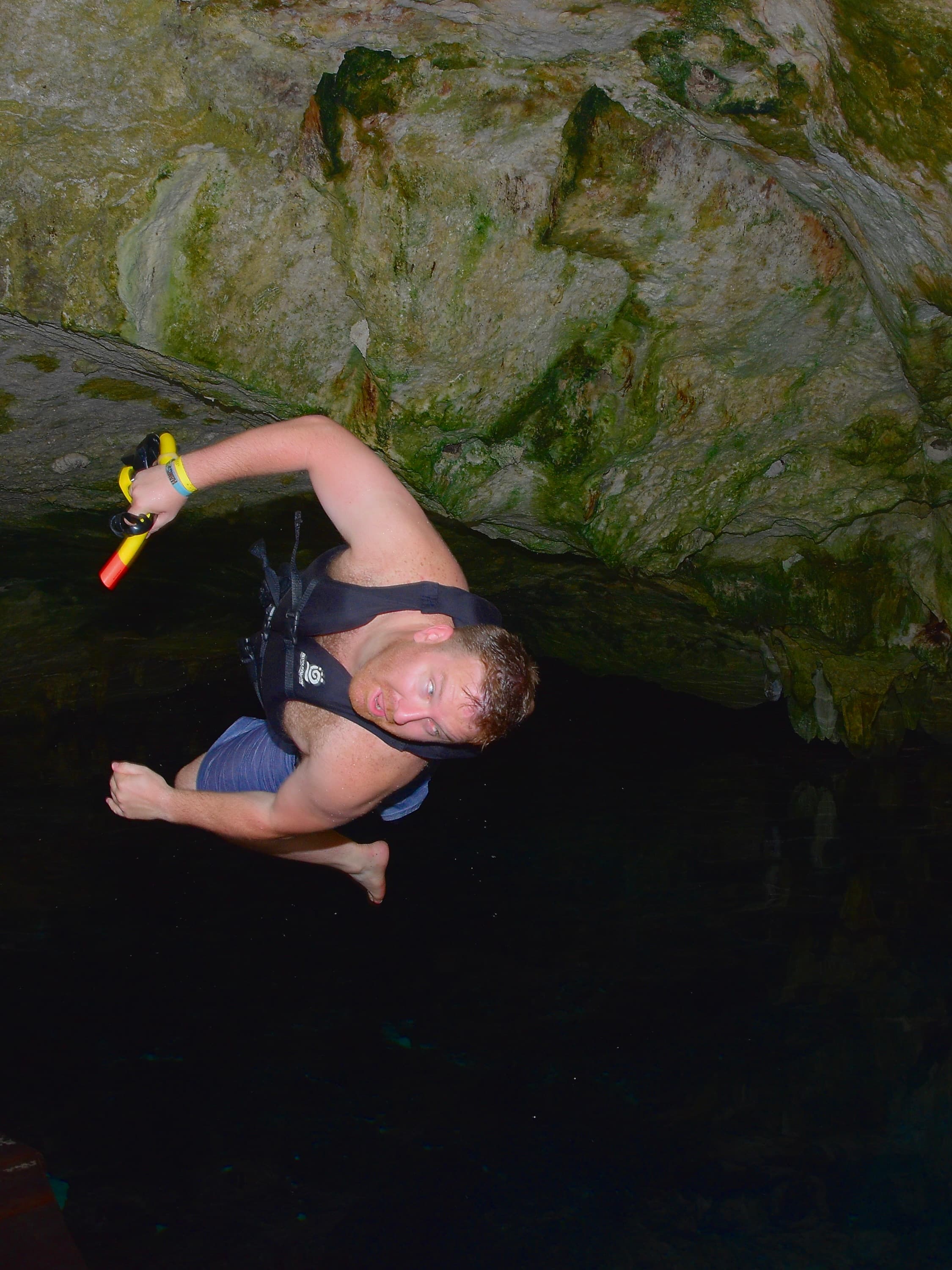 Advisor wearing a life vest in a dark rocky cave at night