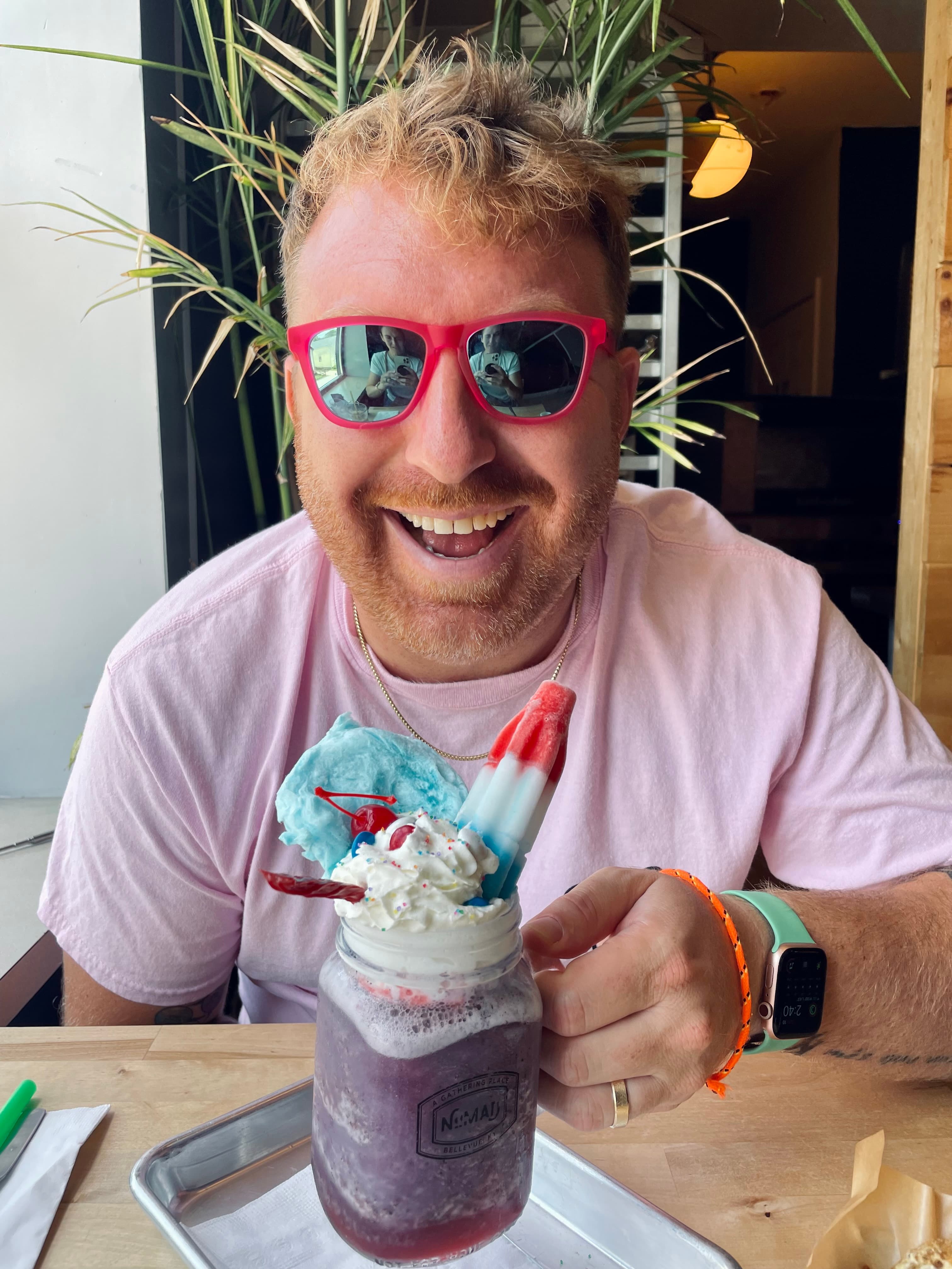 Advisor wearing pink sunglasses in front of a frozen purple drink at a restaurant table