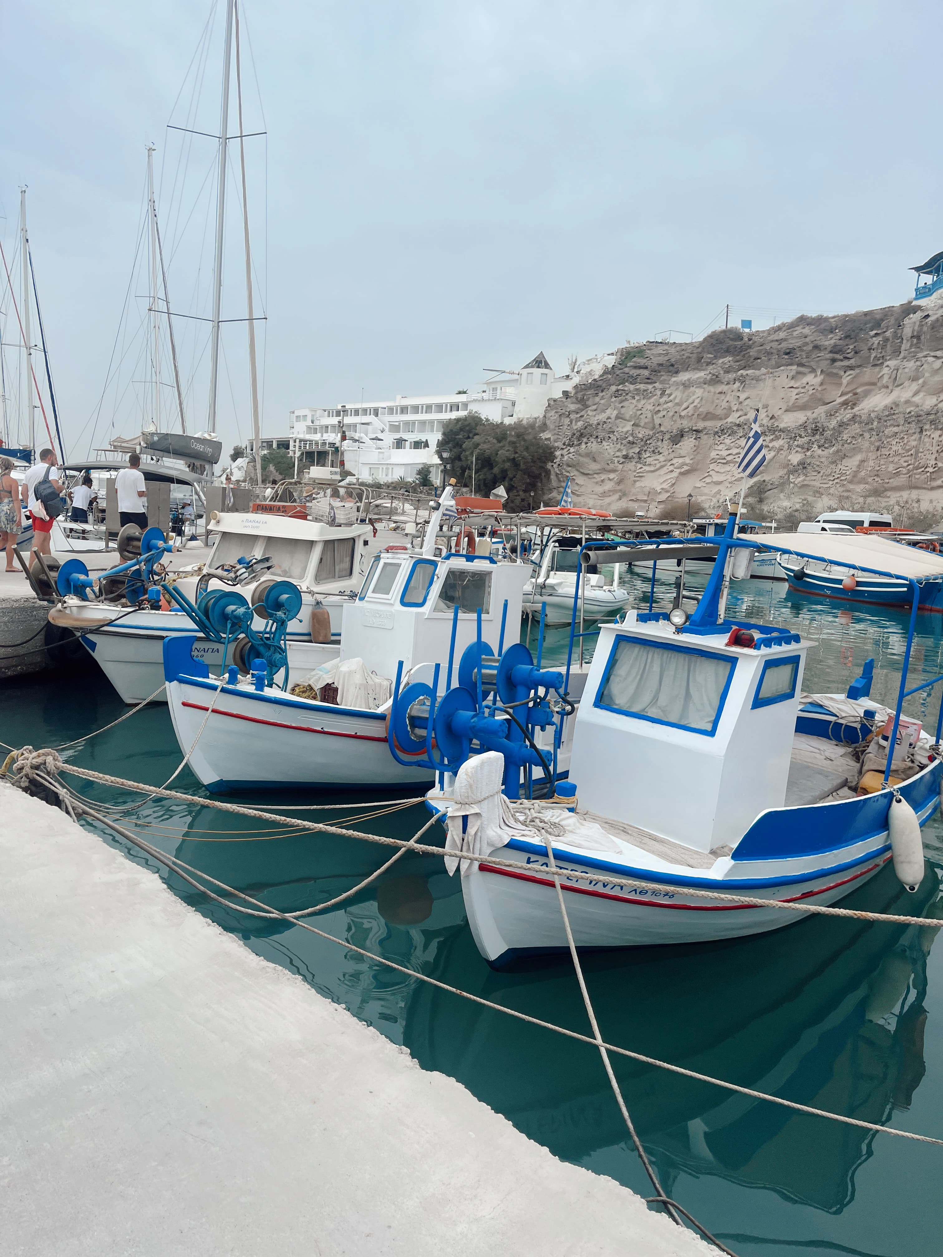 View of a marina with several fishing boats docked in port on a cloudy day