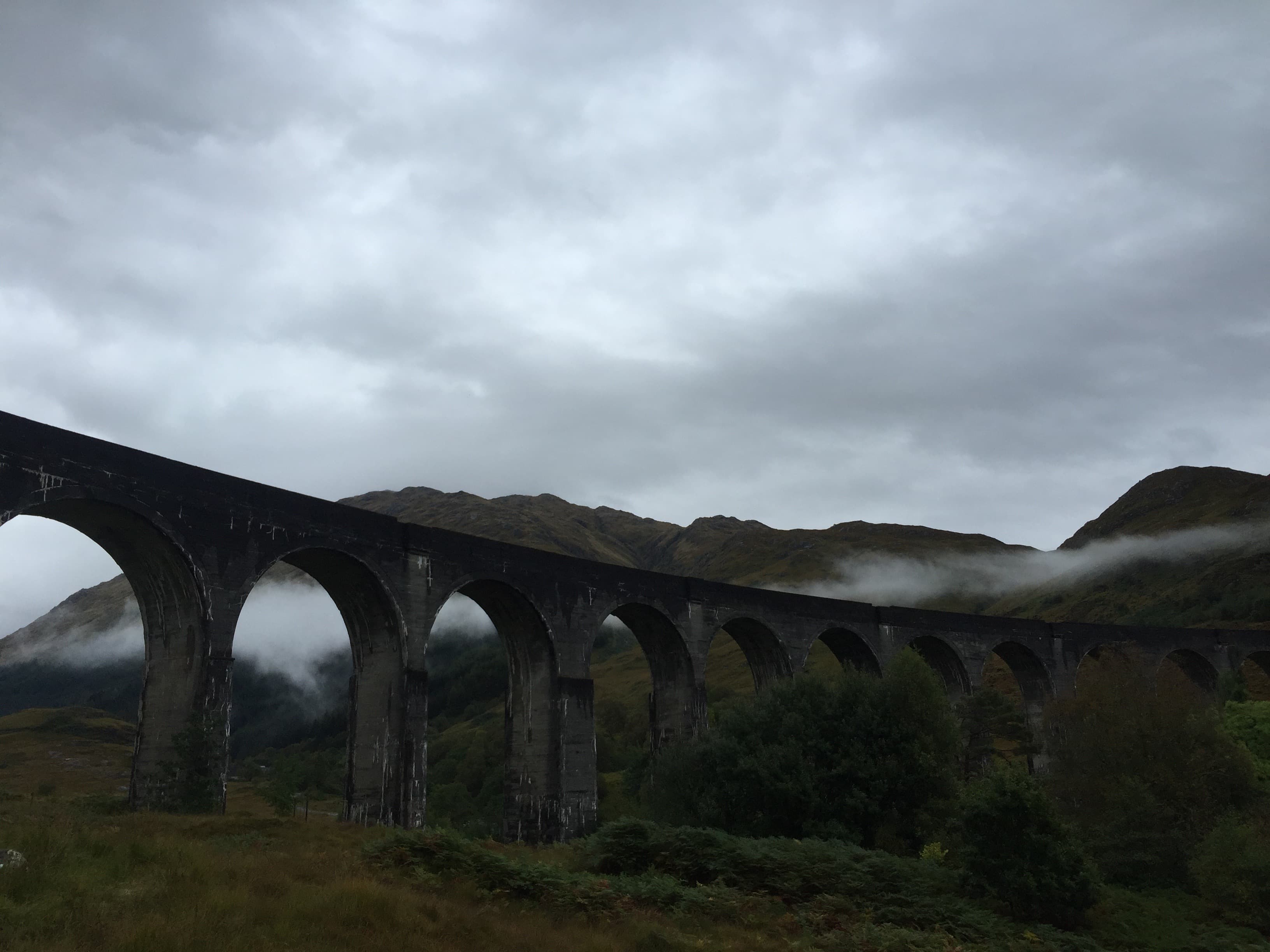 Iconic Glenfinnan Viaduct in Scotland, a stunning railway bridge with arches, nestled amidst scenic mountains.