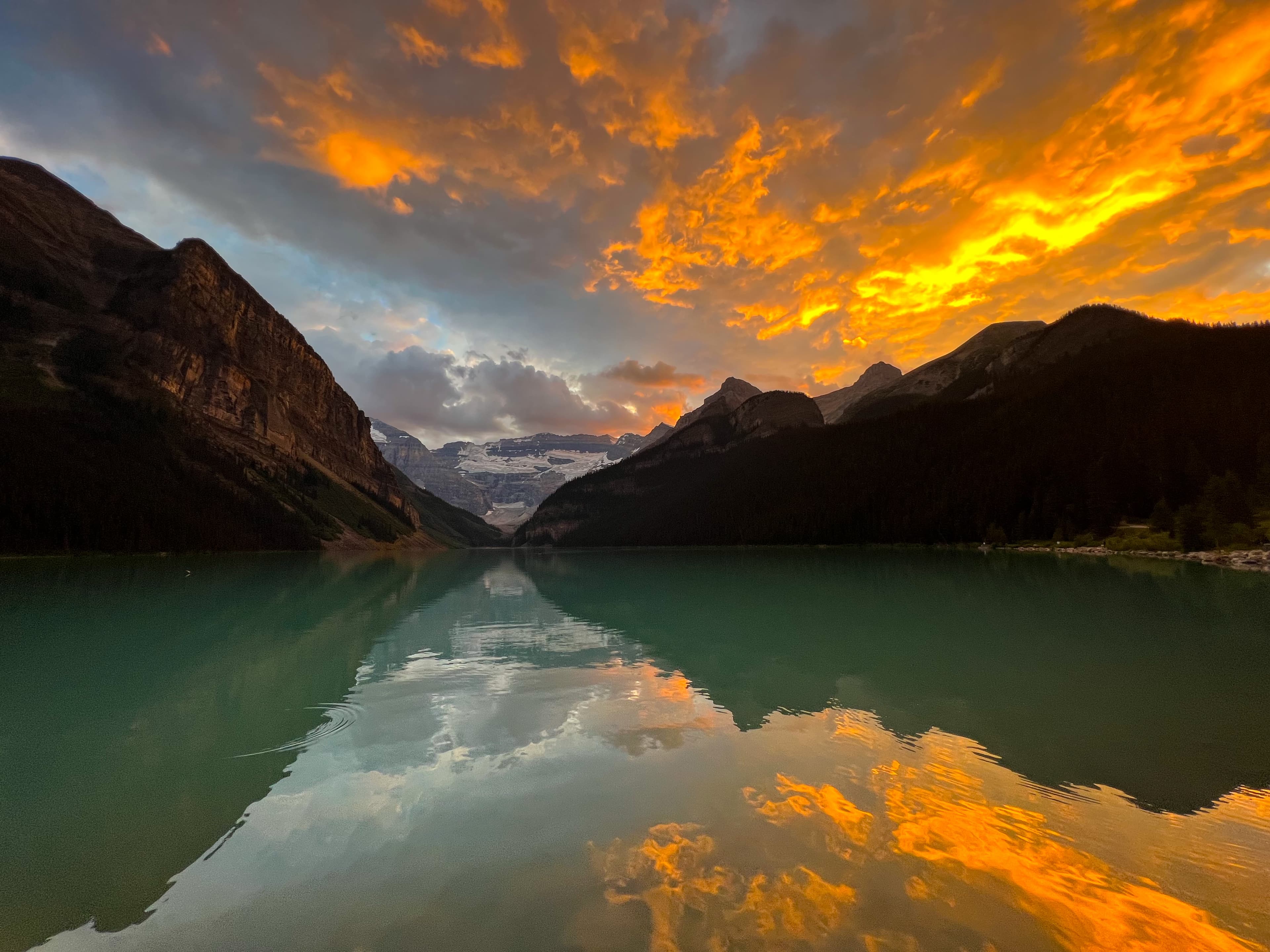 Scenic sunset over lake with mountains in background.
