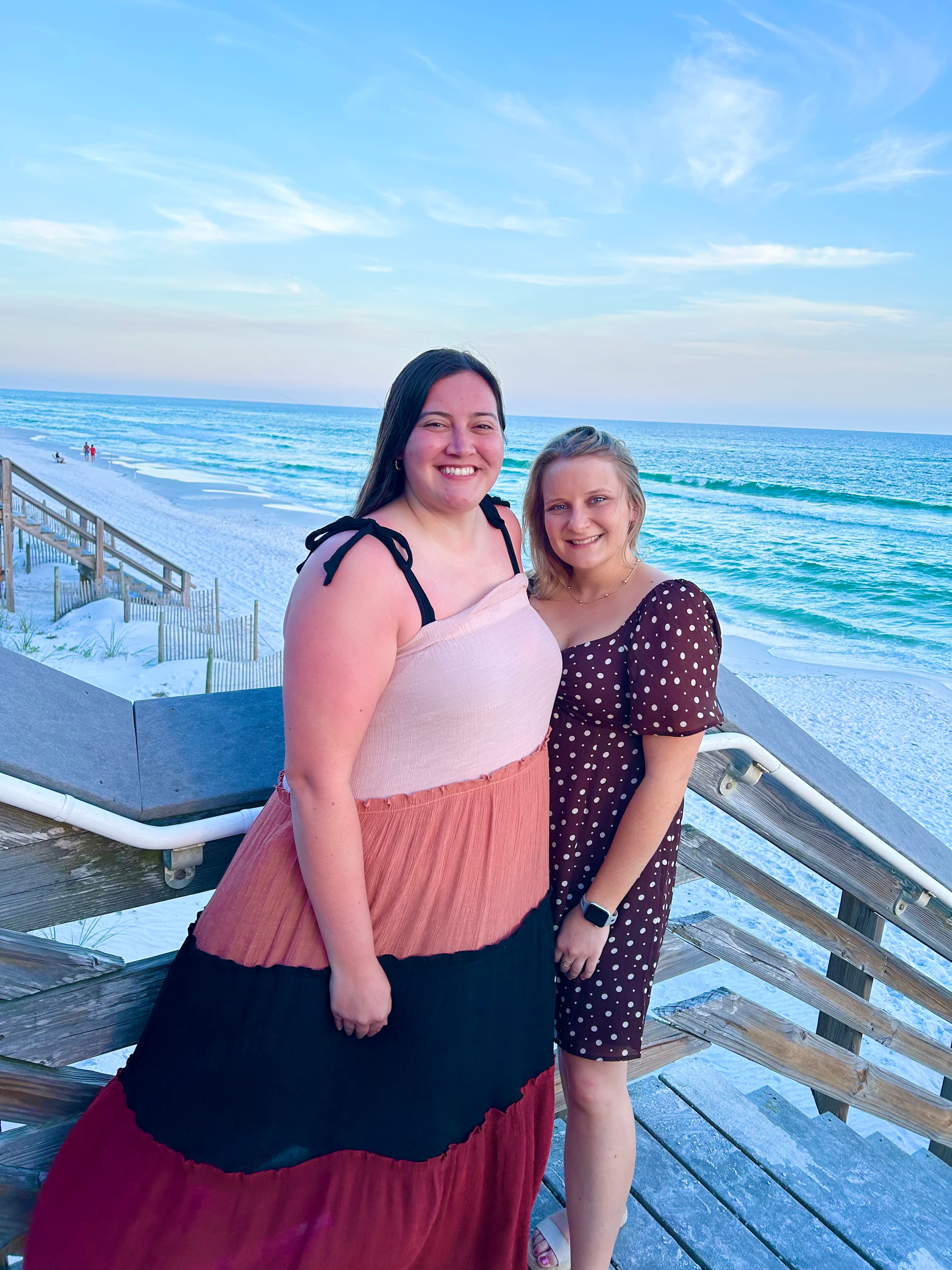 Advisor posing with friend on a pier leading to the beach during the daytime.