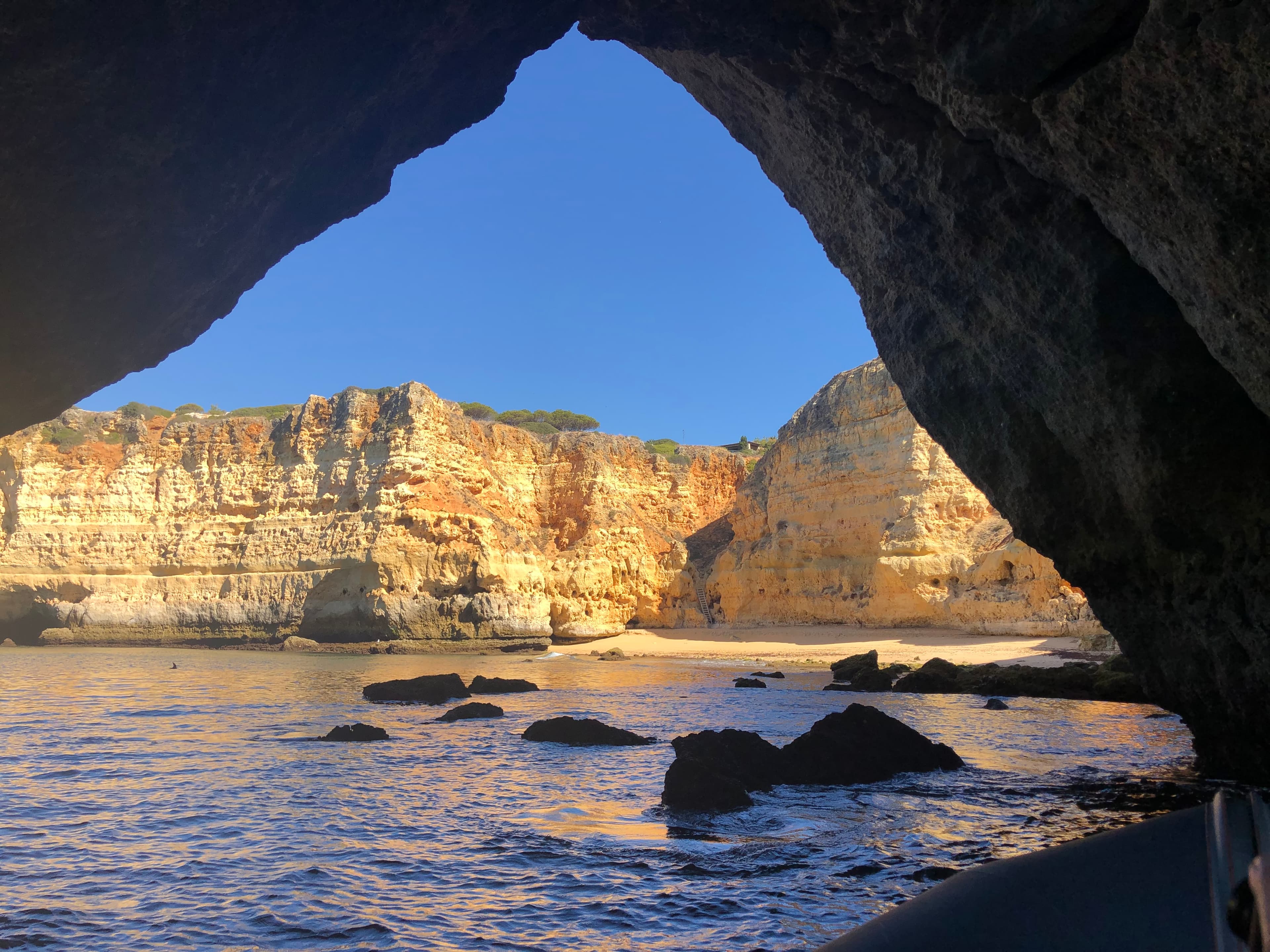 Beautiful view of an empty beach and dramatic cliffs seen underneath a rock formation on a sunny day
