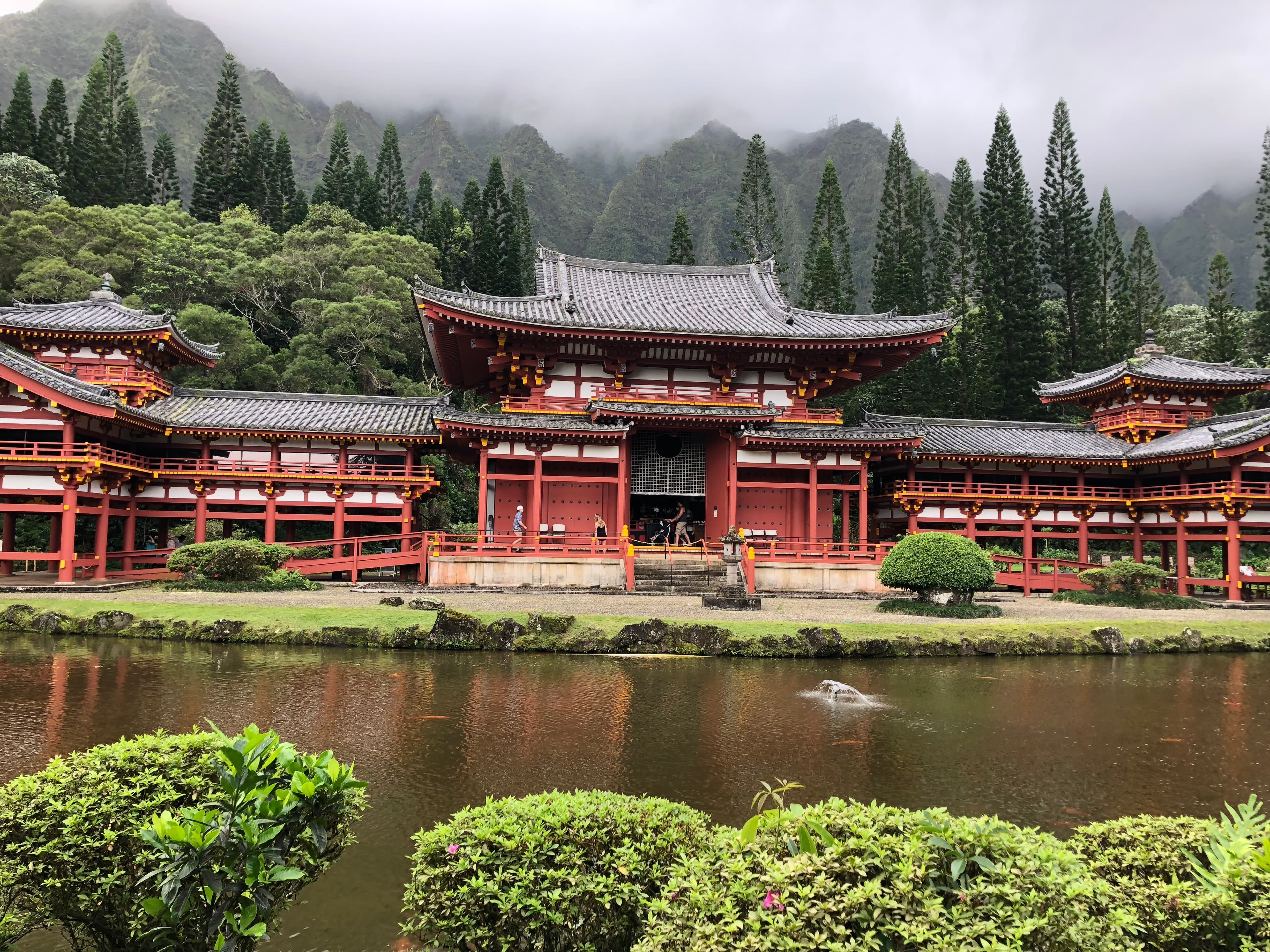 View of a beautiful red temple and pond in the woods on a cloudy day