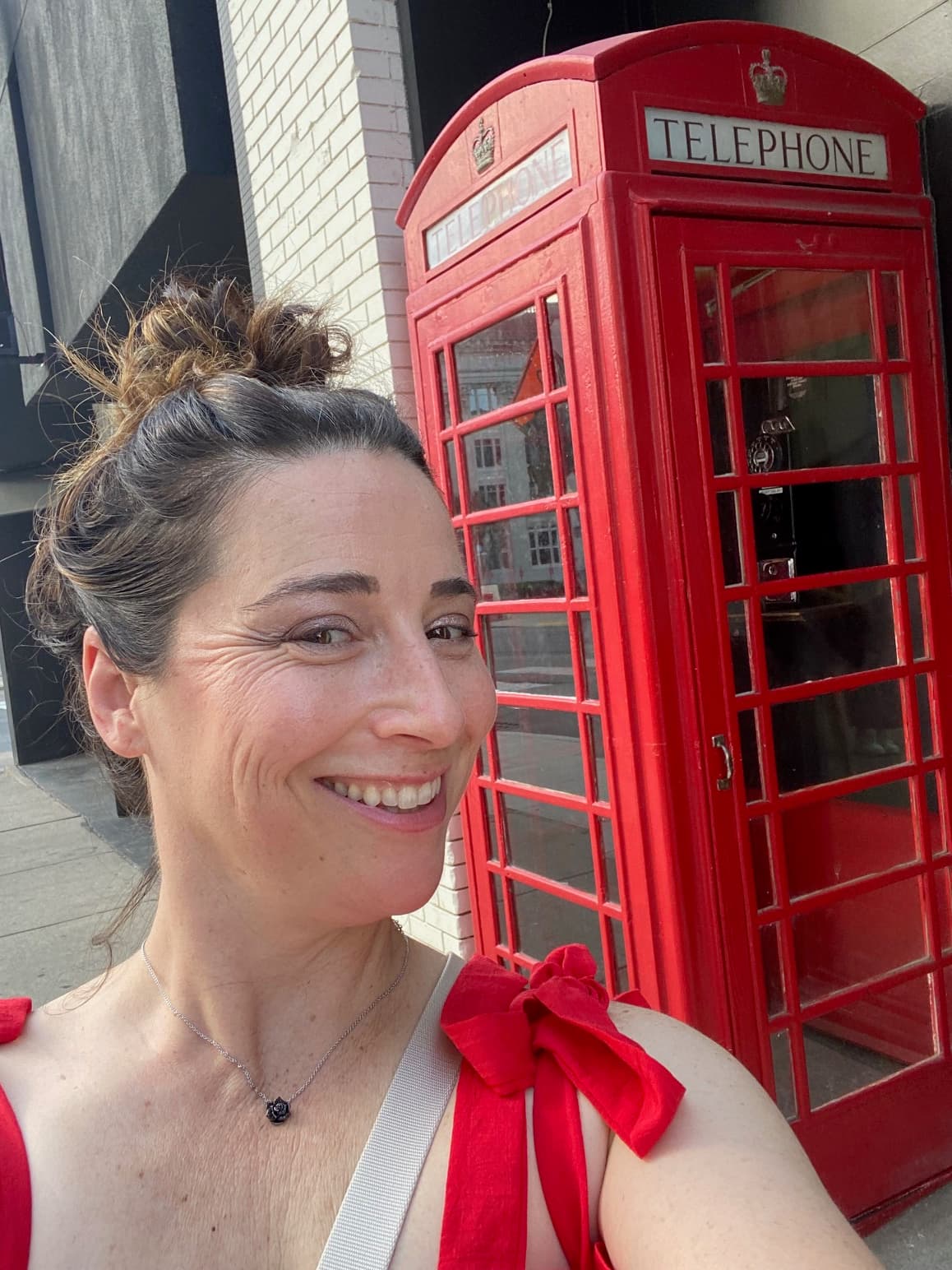 Advisor taking a selfie in front of a red telephone box during the day