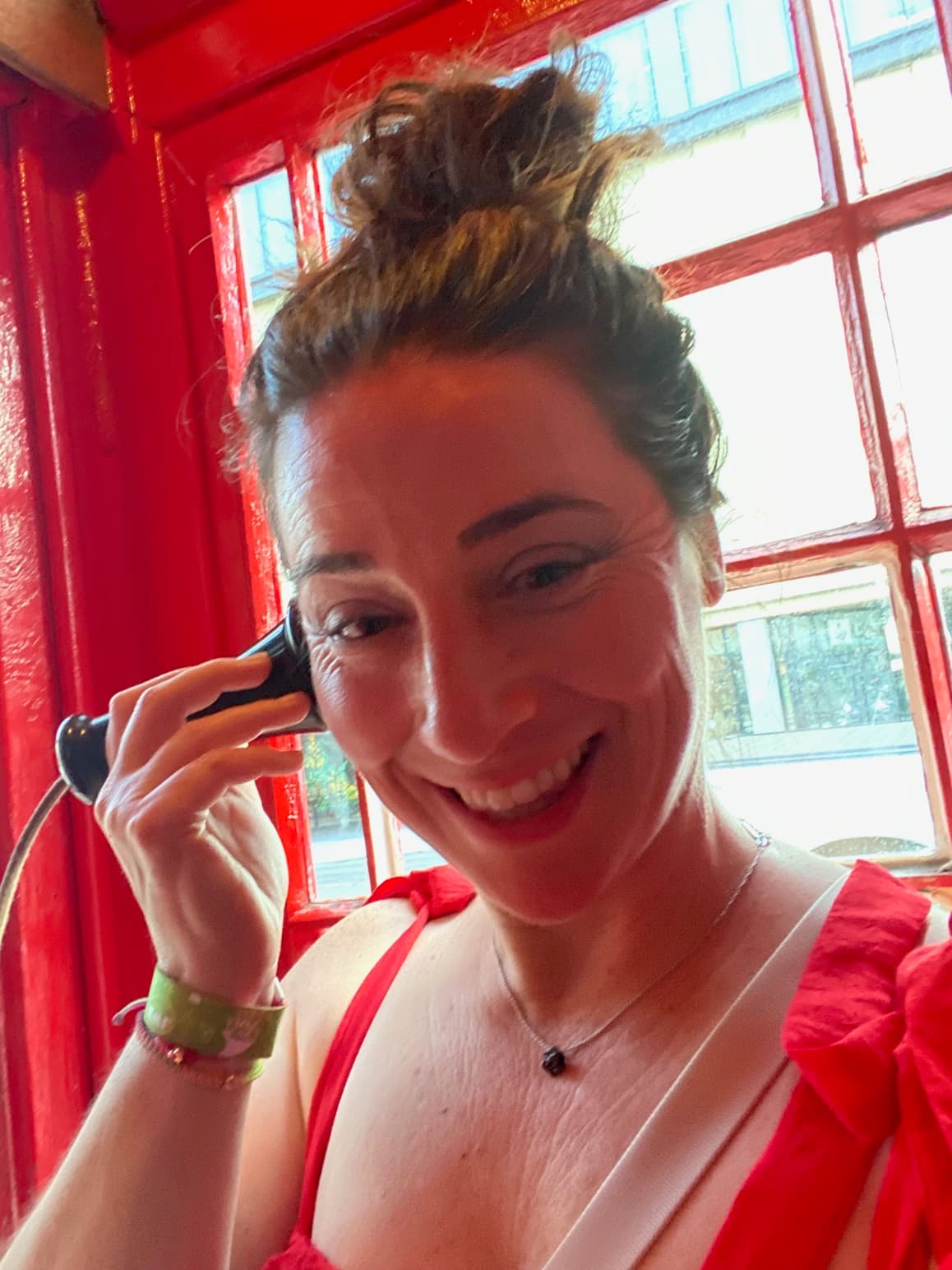 Advisor taking a selfie holding an old-fashioned telephone to her ear inside a telephone box
