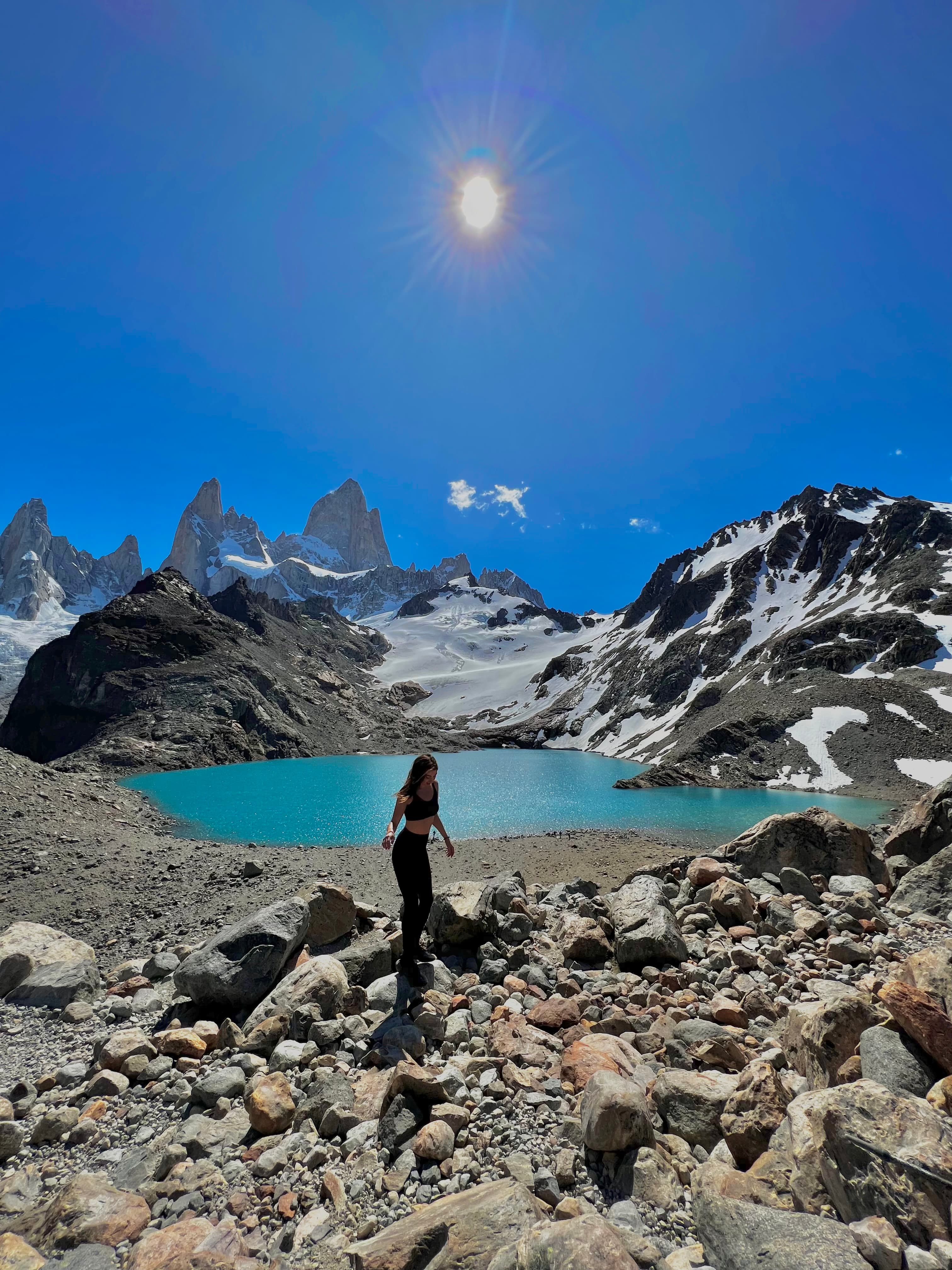 Camille hiking in a mountainous environment with a beautiful blue lake and clear skies behind her