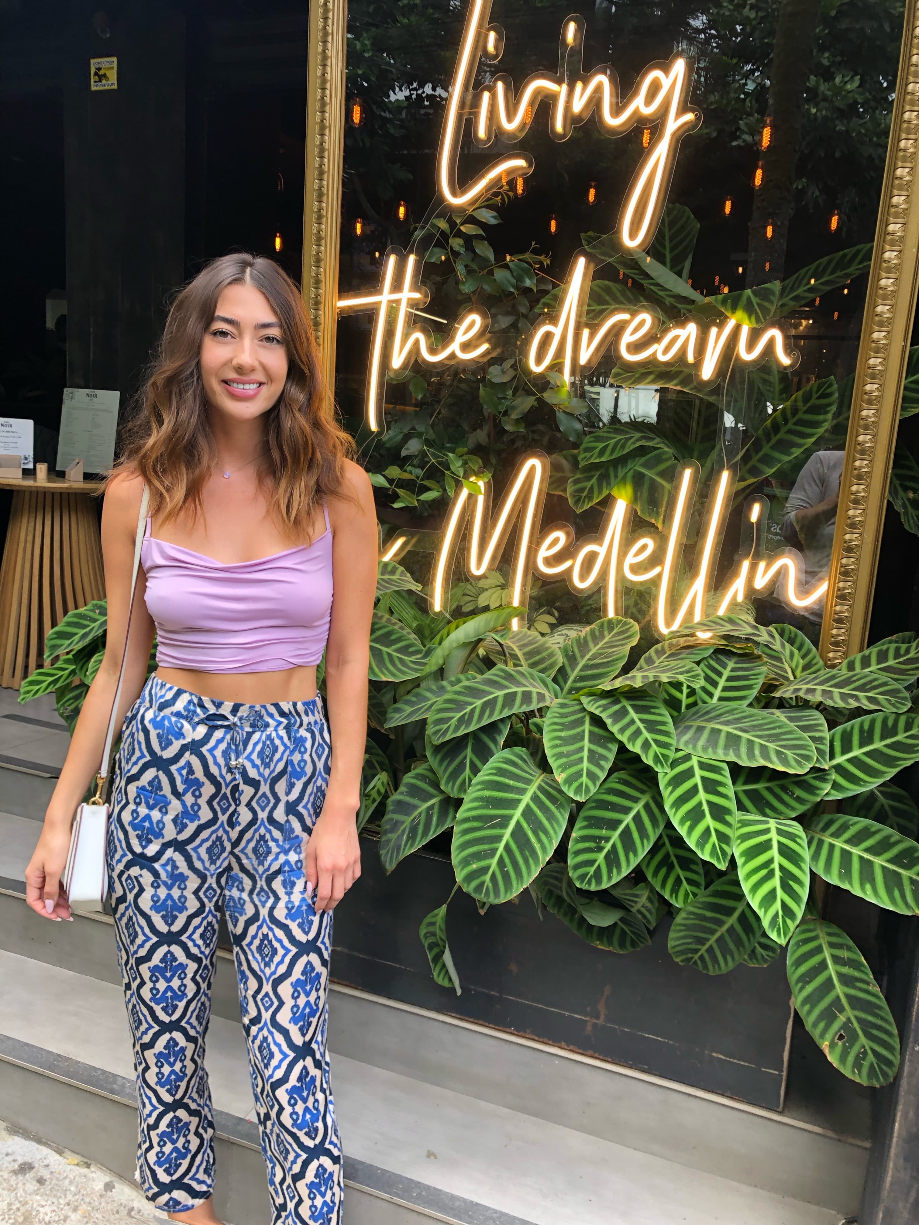 Camille on the street in front of a lighted sign reading “Living the dream in Medellín”
