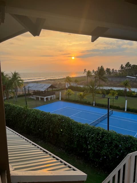 View of an empty resort pool overlooking the beach at sunset