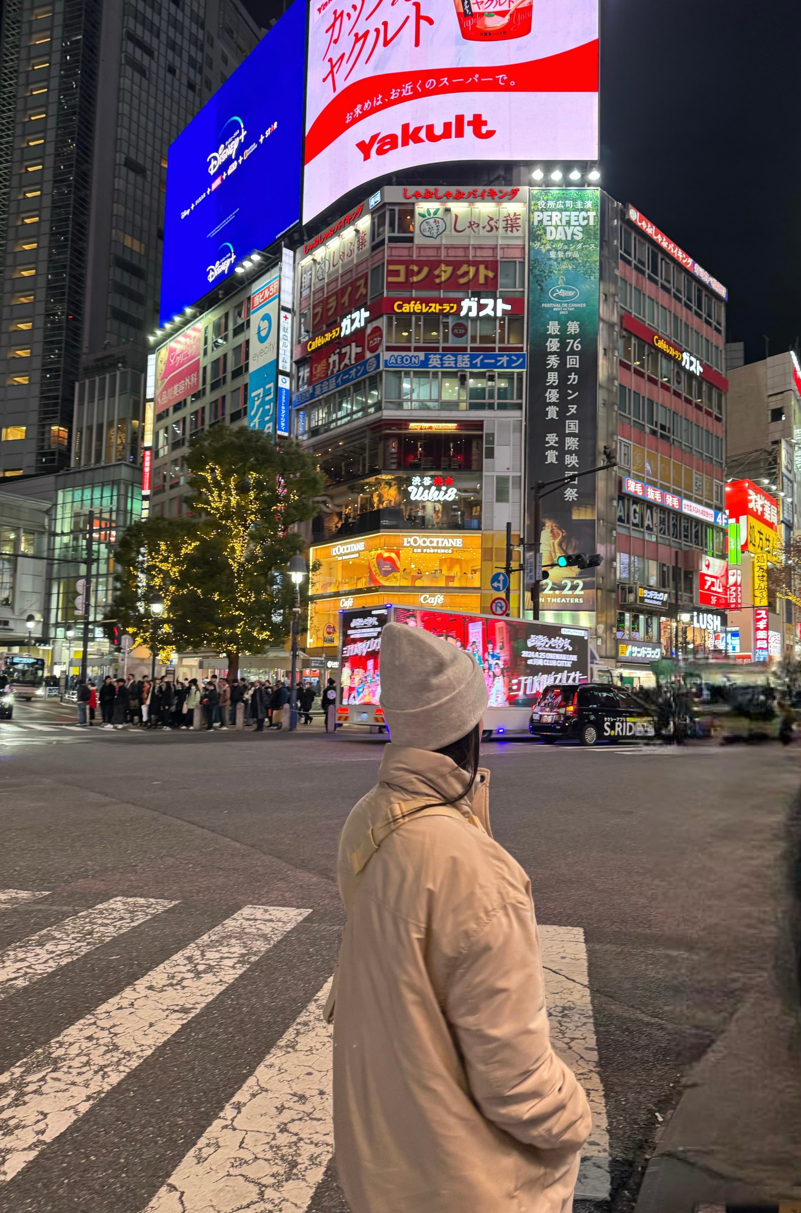 Advisor in winter clothing crossing the street in a city with bright billboards in the background