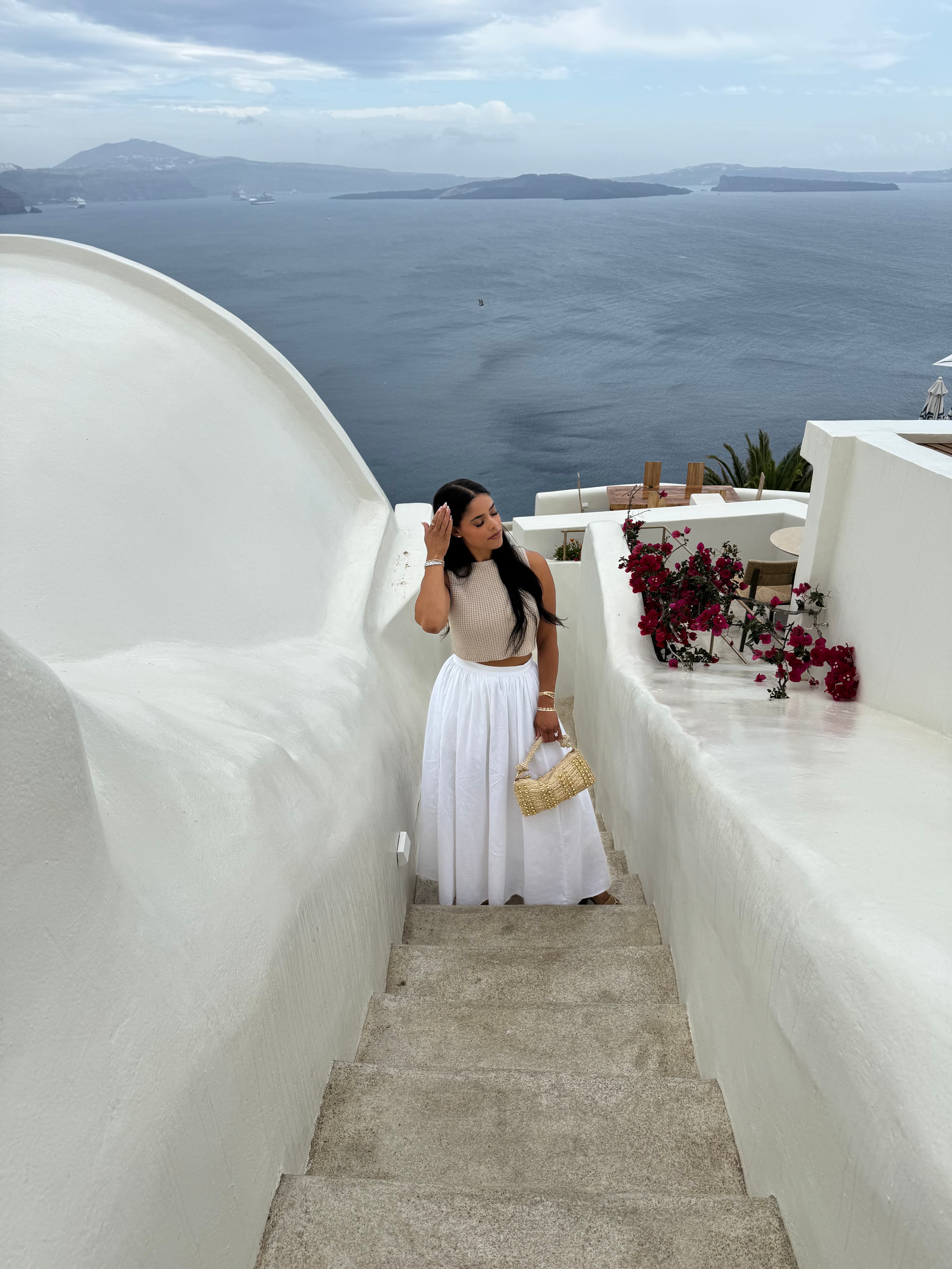 Advisor in a long white skirt seen from above climbing stairs overlooking the sea