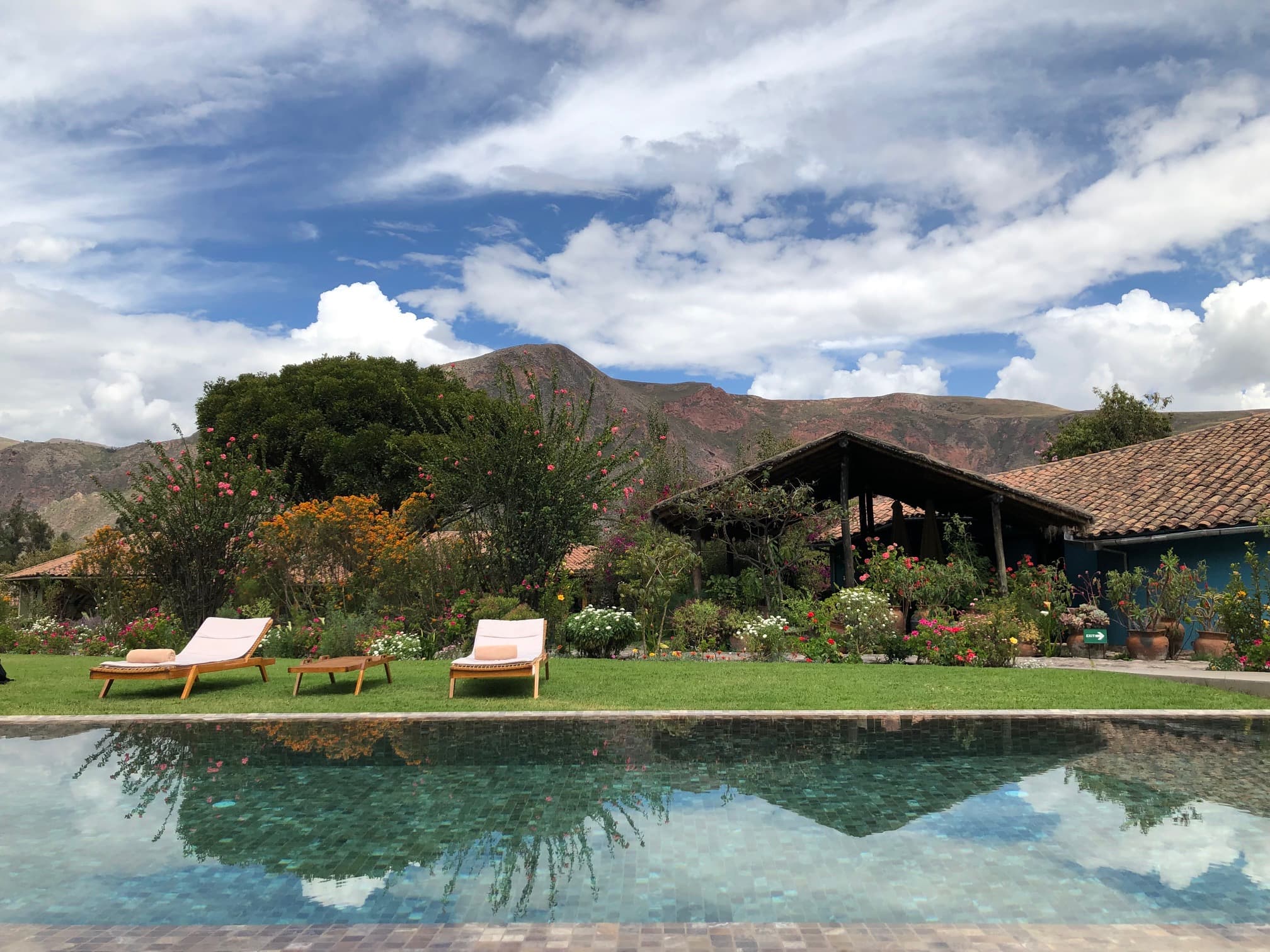 View of a beautiful resort pool and two white lounge chairs in the countryside on a sunny day