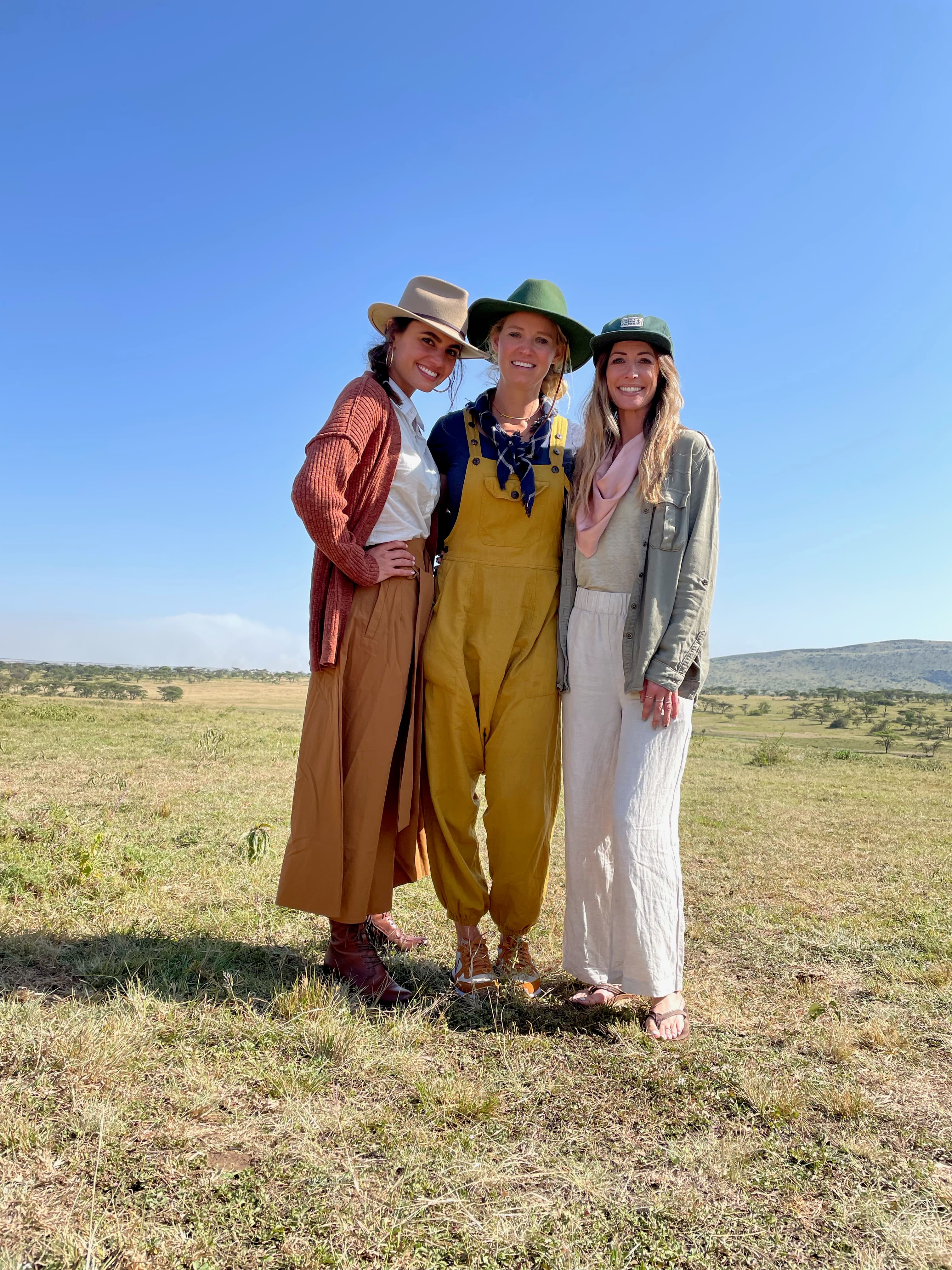 Jill and two women posing side by side in an open grassy area on a sunny day