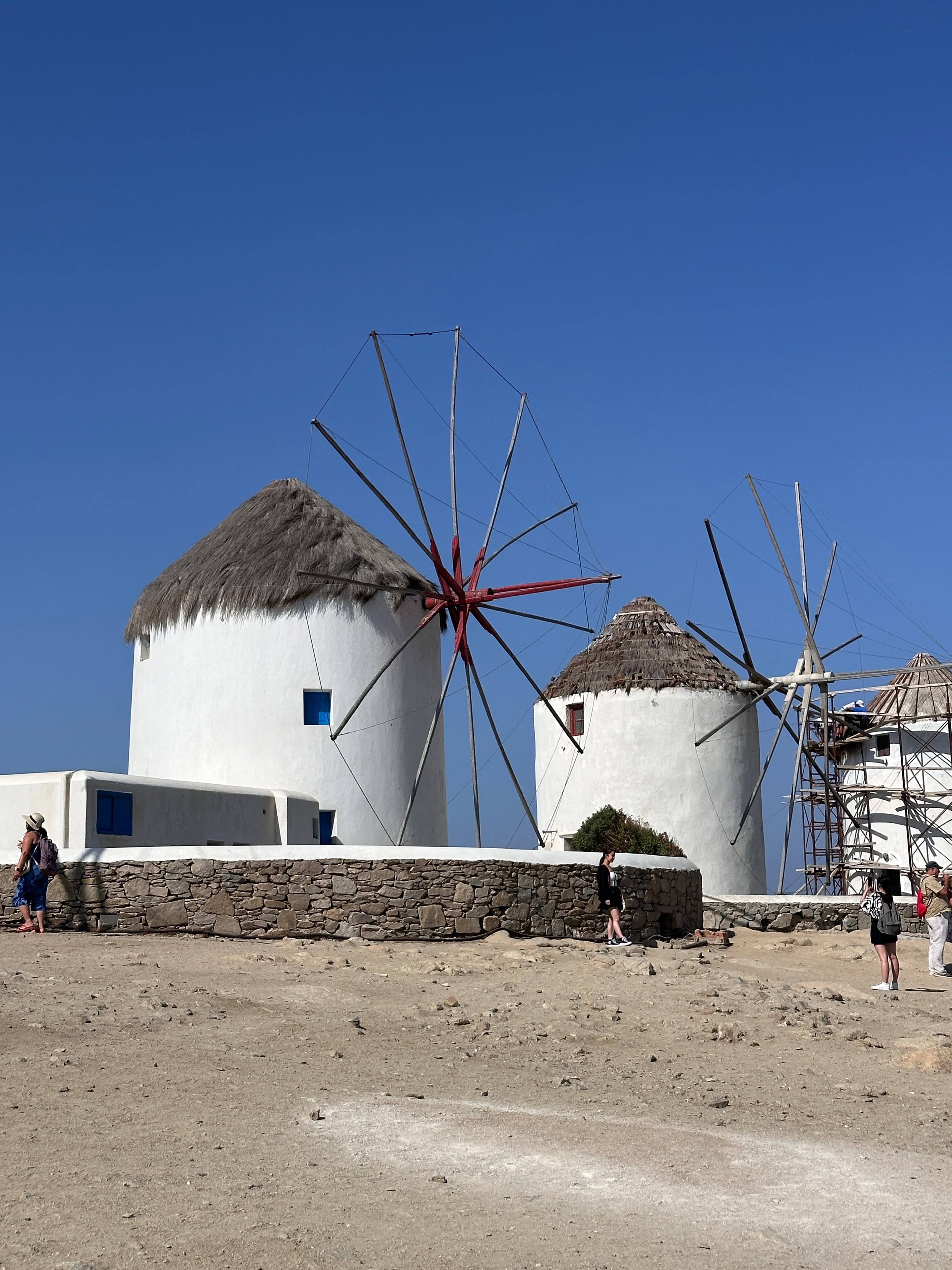 View of three old-fashioned windmills with thatched rooftops on a clear day