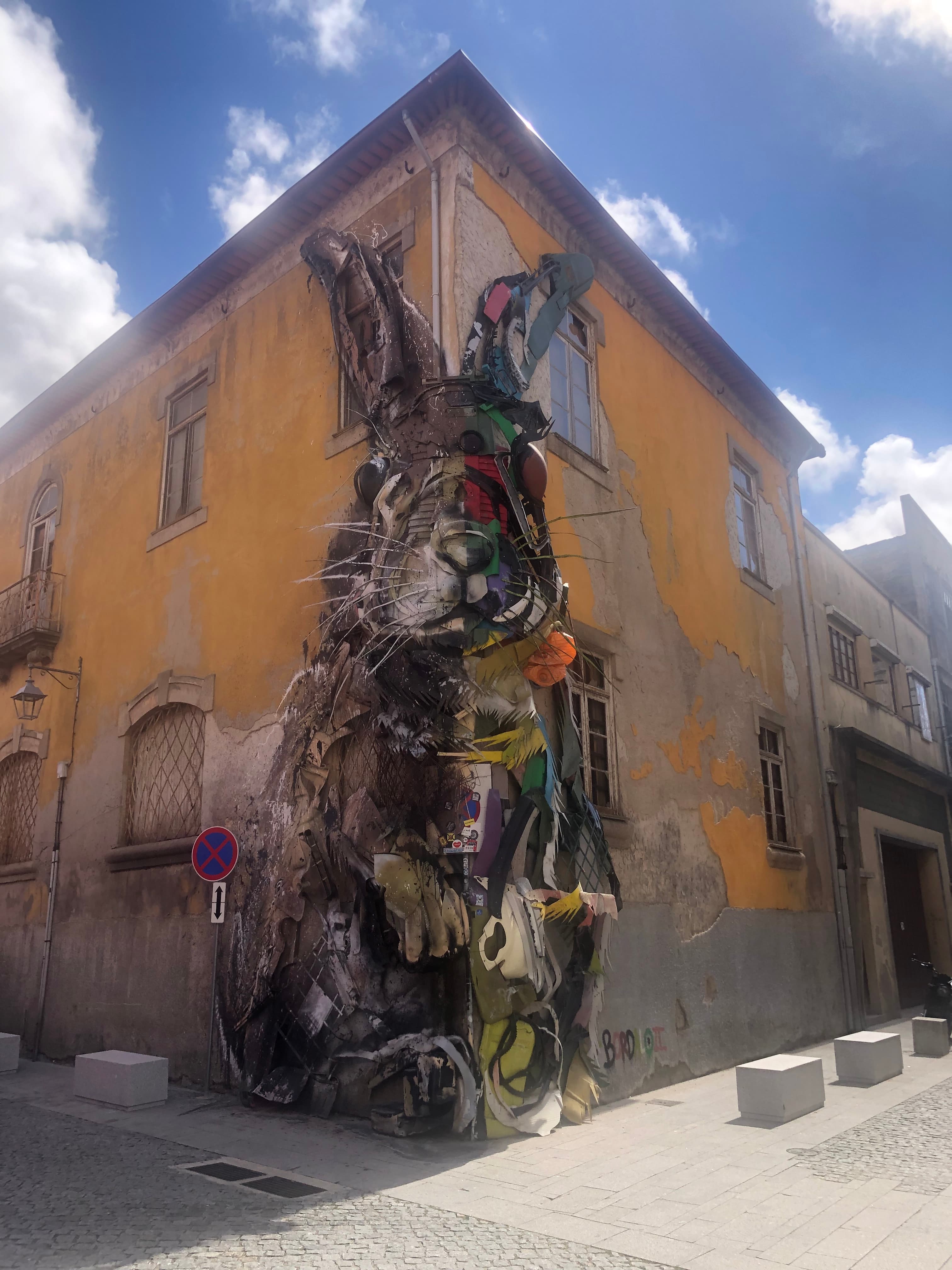 View of the corner of a yellow building with a mural of a large rabbit on a sunny day