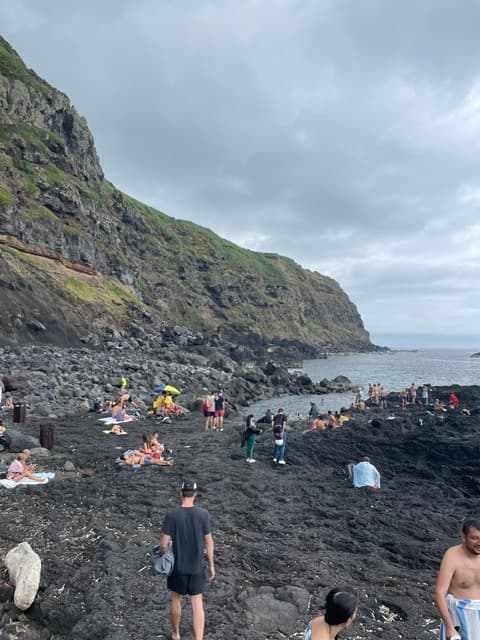 A view of a black sand beach on a sunny day.