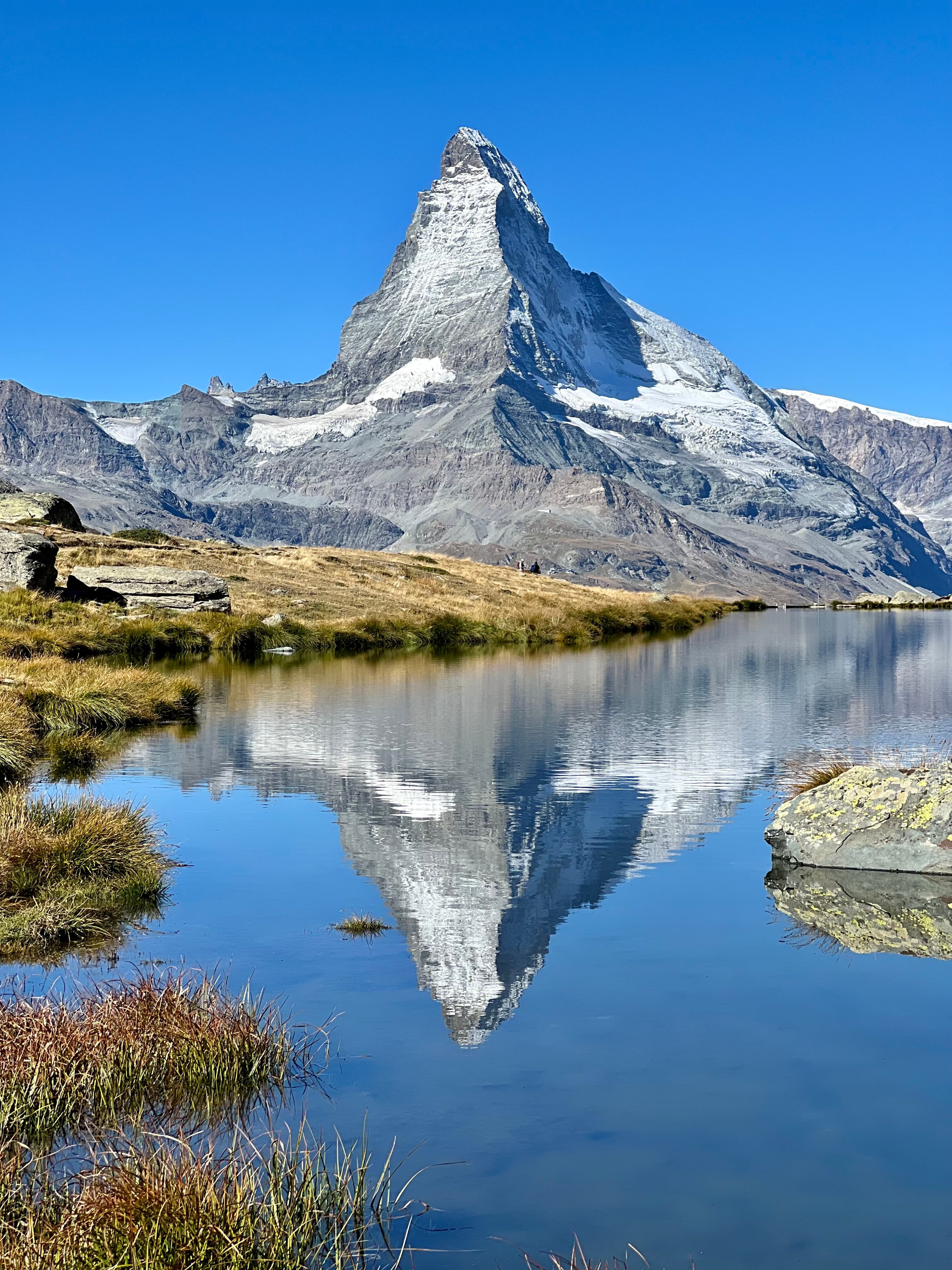 Snowy mountainous cliff over water.
