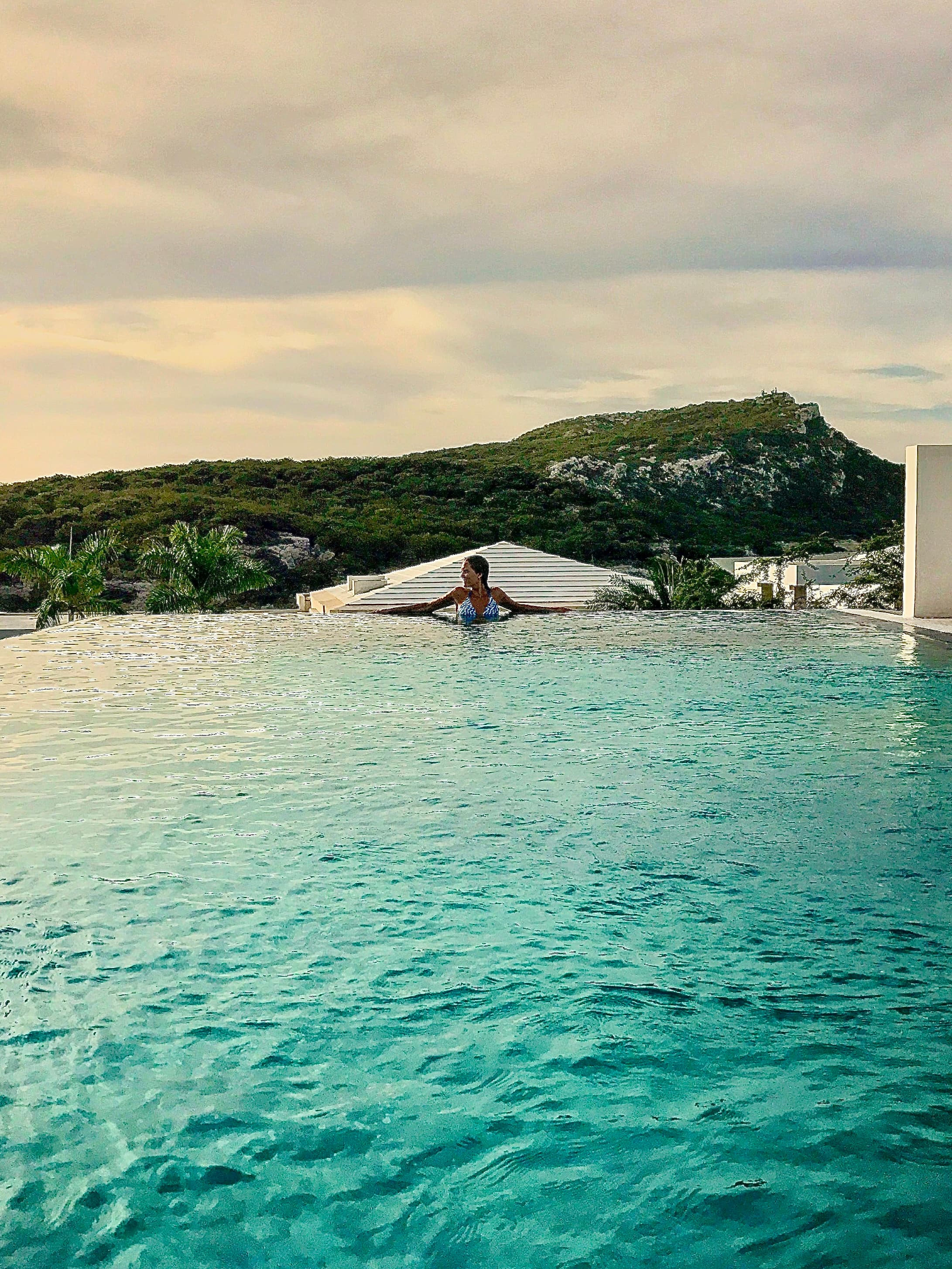 View of advisor in an infinity pool overlooking lush green mountains