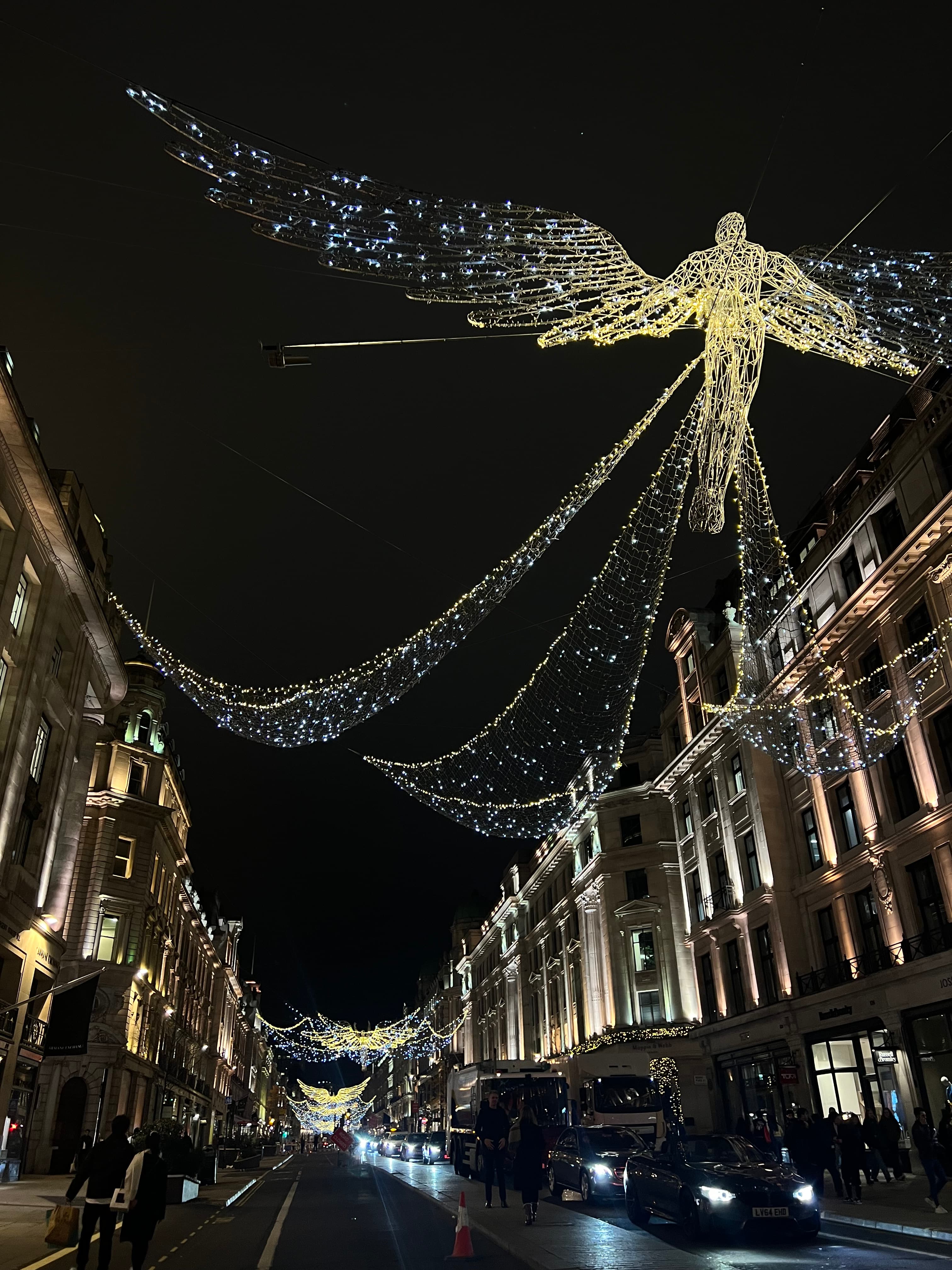 View of string lights between buildings lining a city street at night