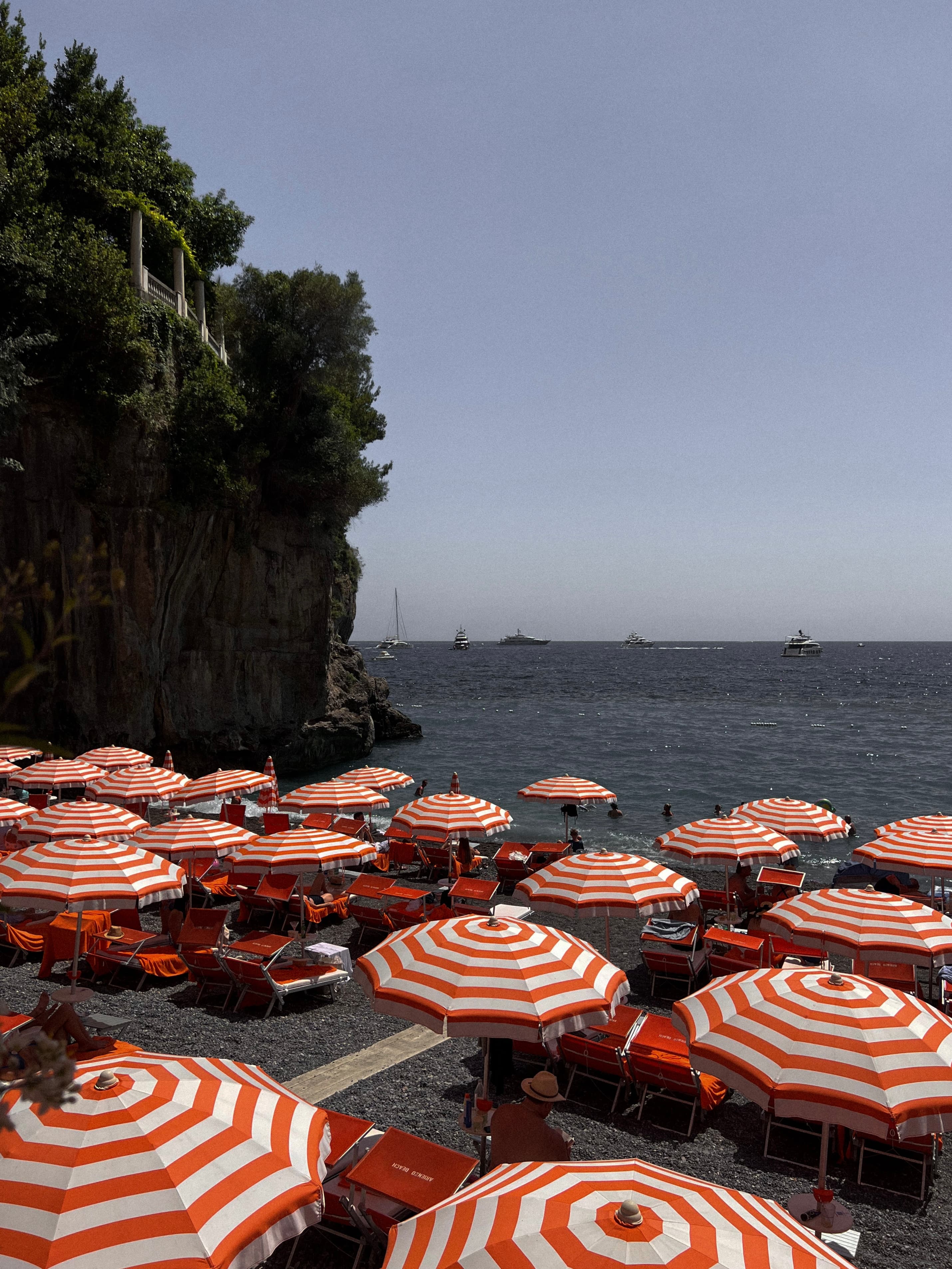 View of red and white striped umbrellas on the beach next to steep cliffs