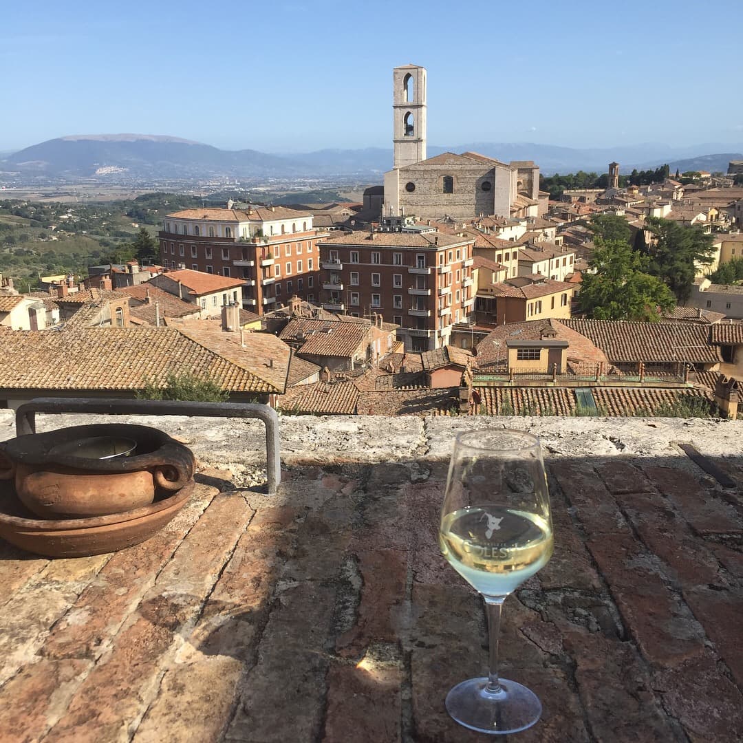Glass of white wine on a balcony overlooking a small town in the country under clear skies