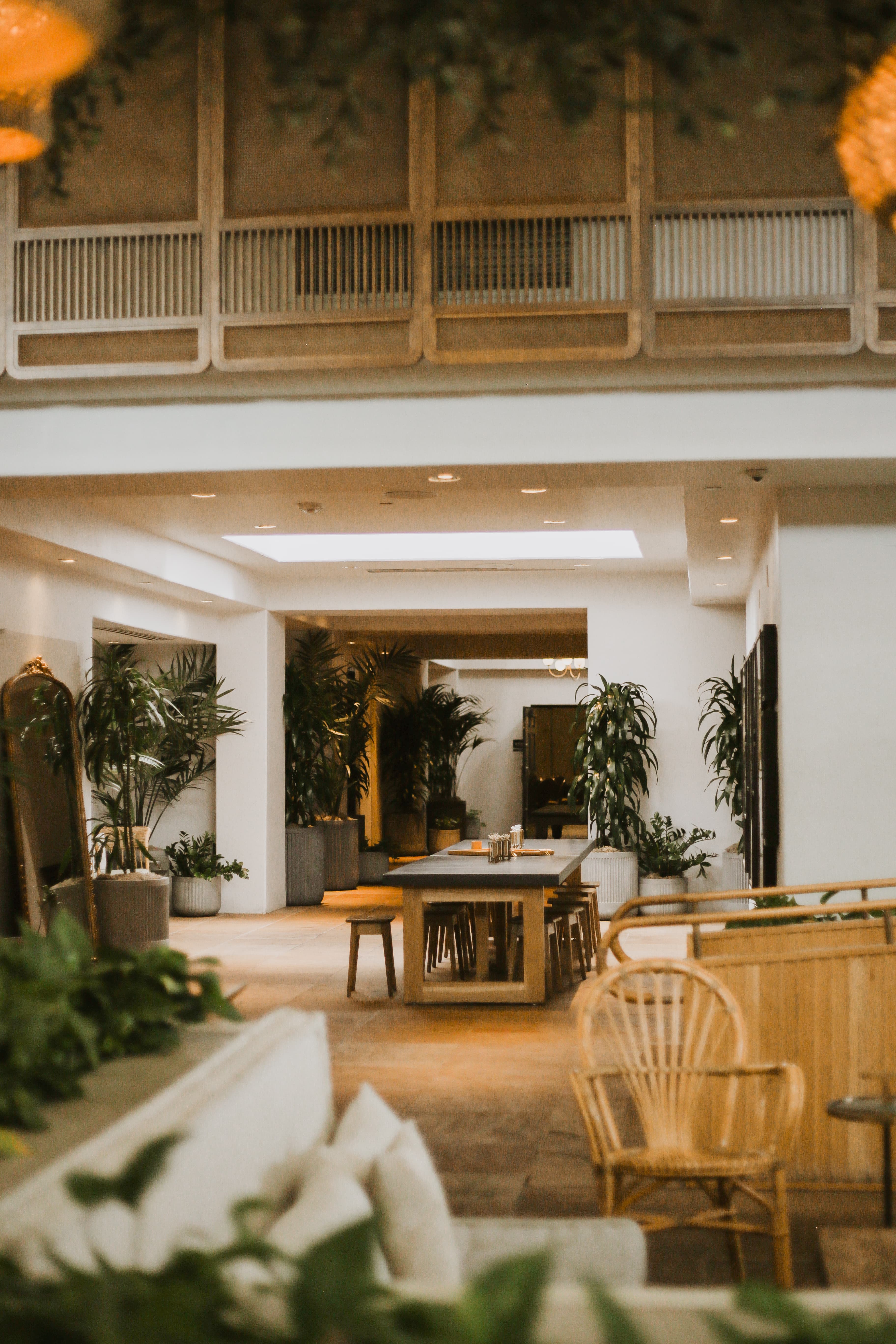View of the interior of a hotel lobby with wooden furniture and plants throughout