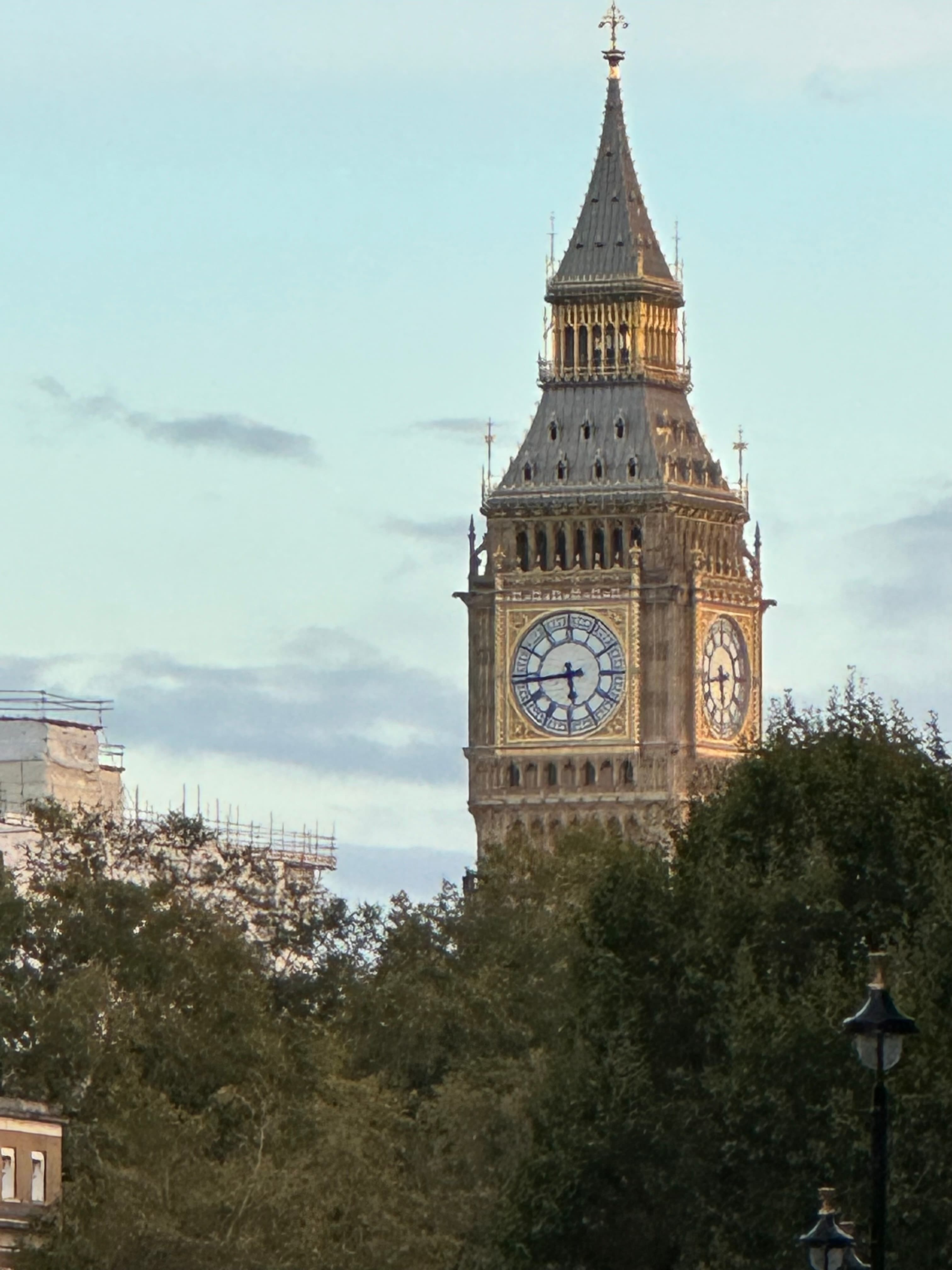 Close up view of the top of Big Ben and nearby trees on a sunny day in London