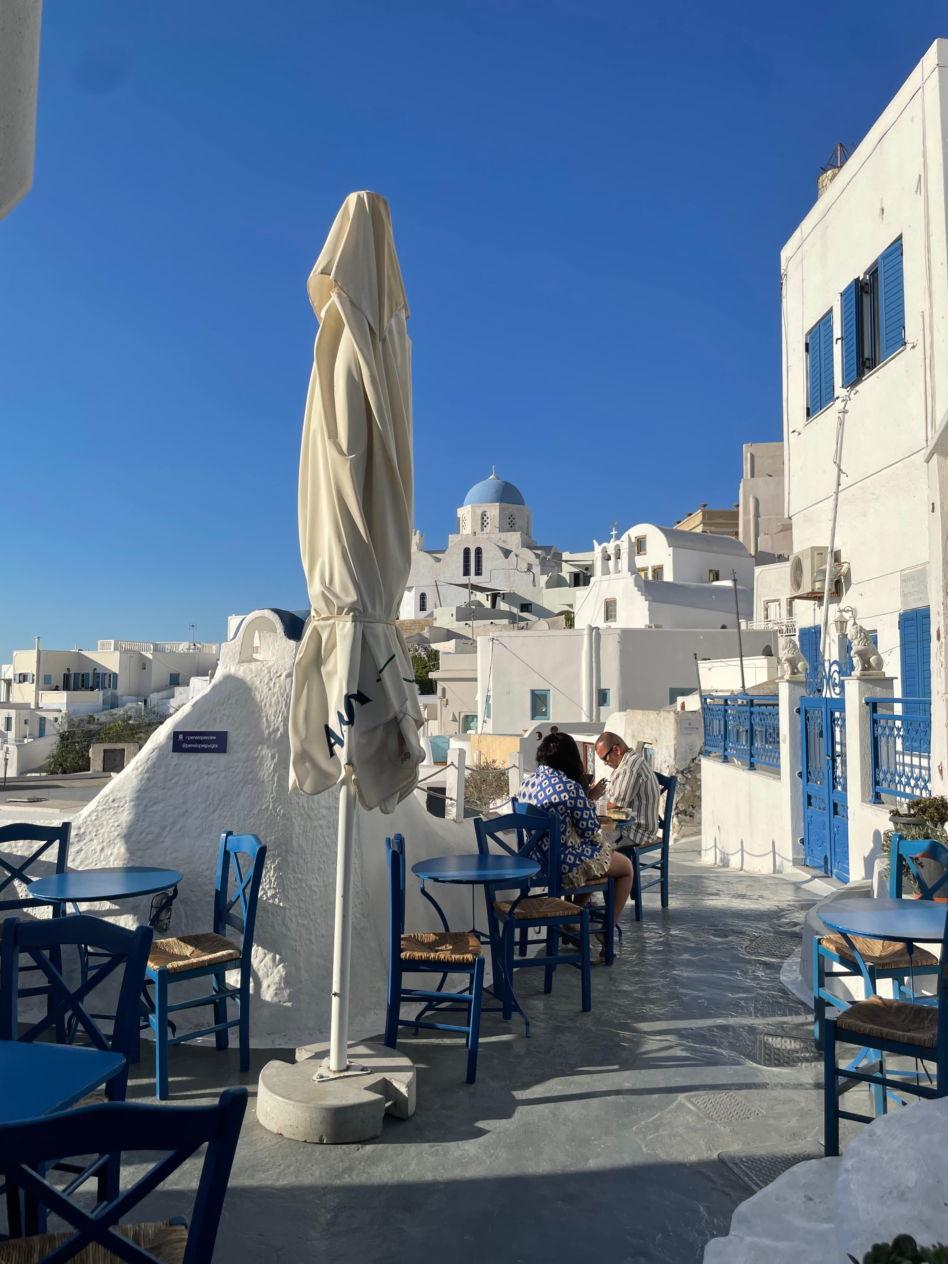 View of an outdoor restaurant patio alongside white buildings on a sunny day