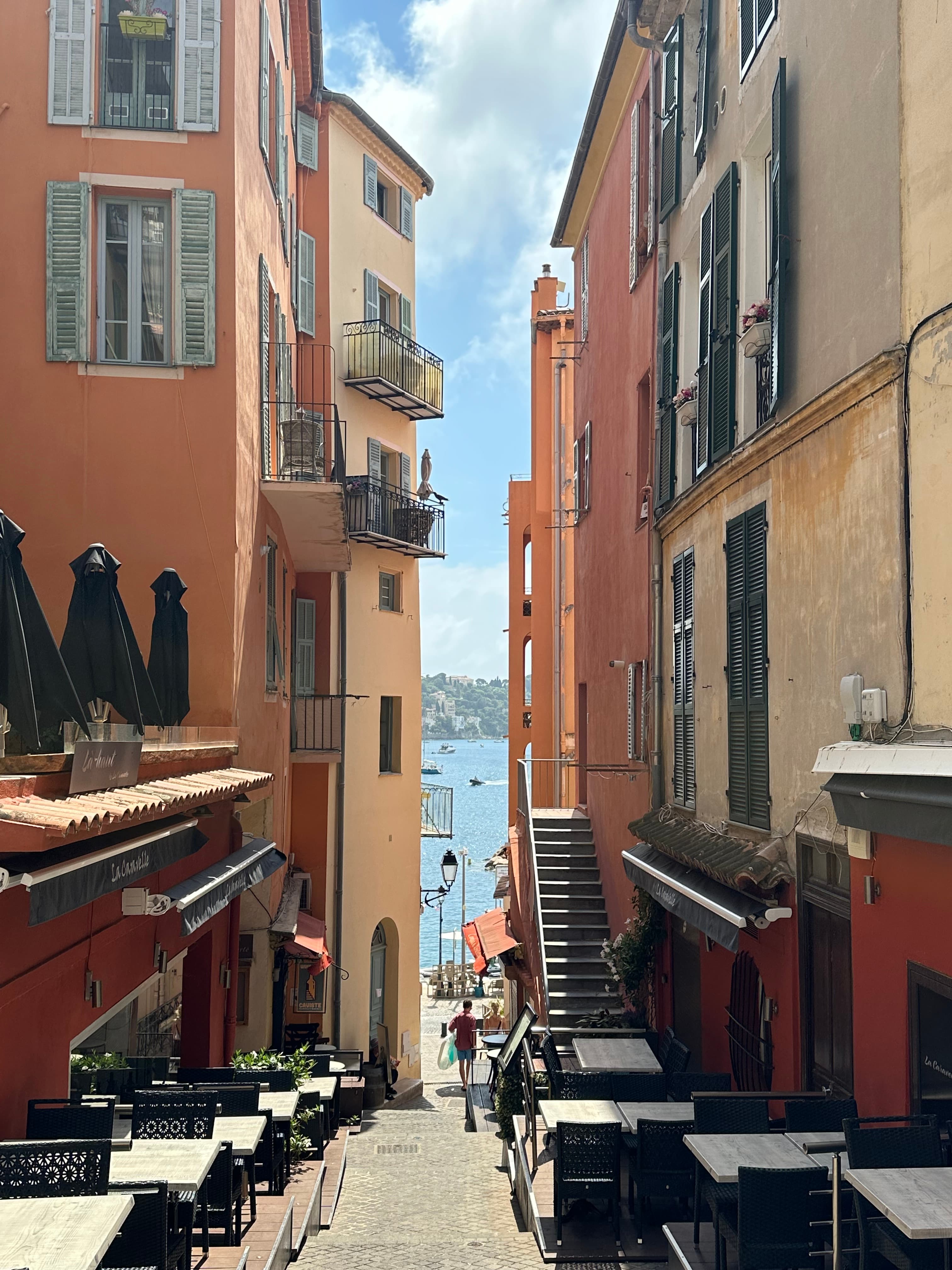 View of a narrow street leading down to the sea on a sunny day