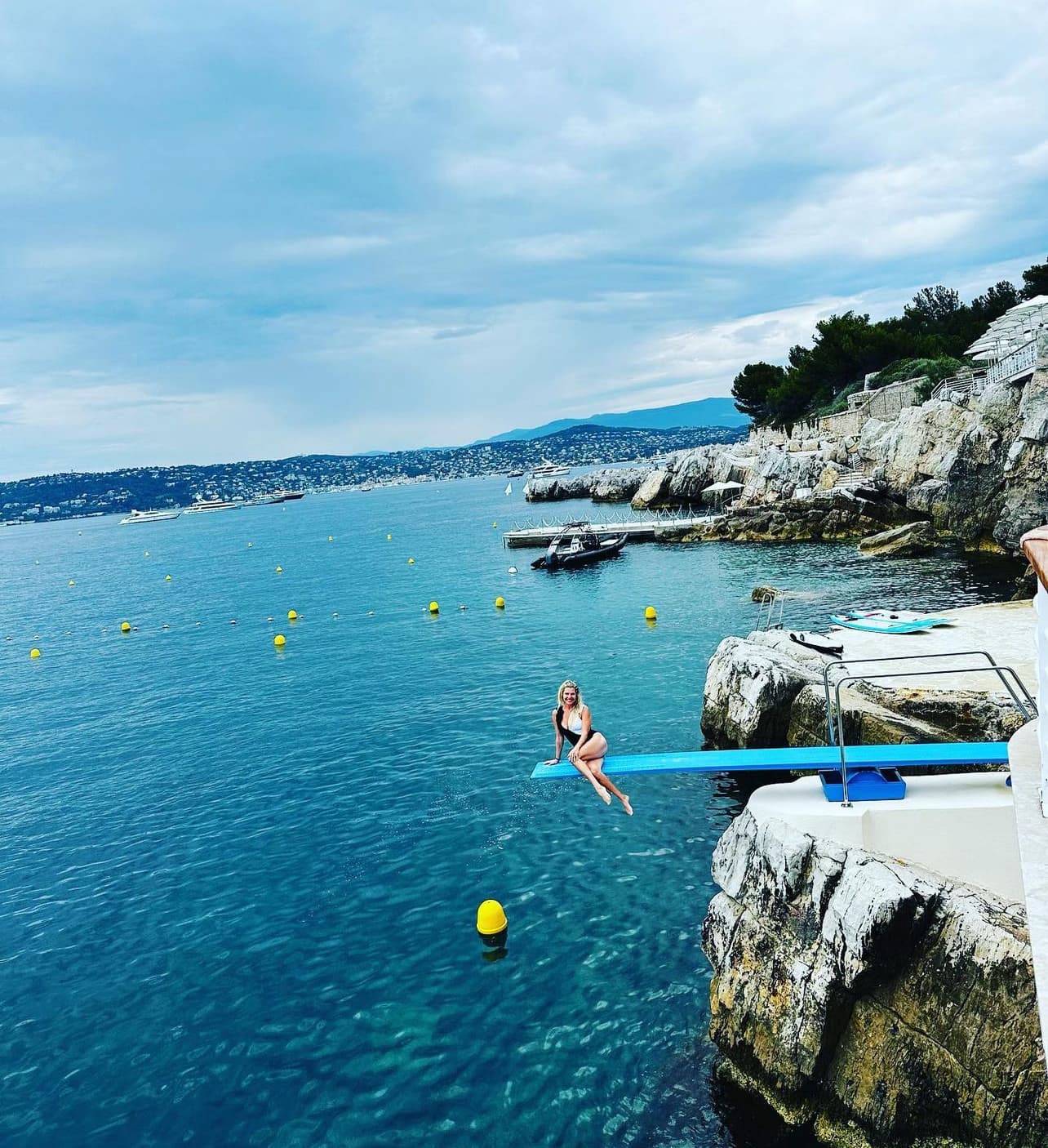 View of advisor sitting on the edge of a diving board overlooking a beautiful coastal area on a cloudy day