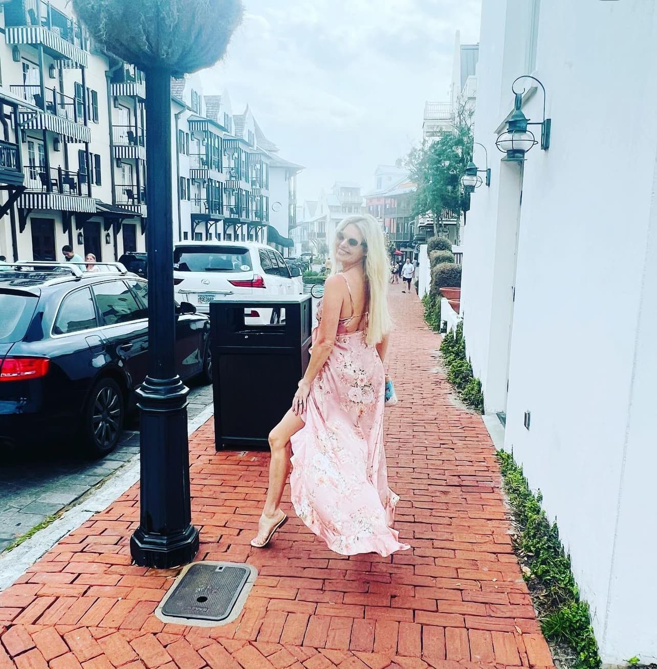 Advisor in a long pink dress posing on the sidewalk of a city street during the day
