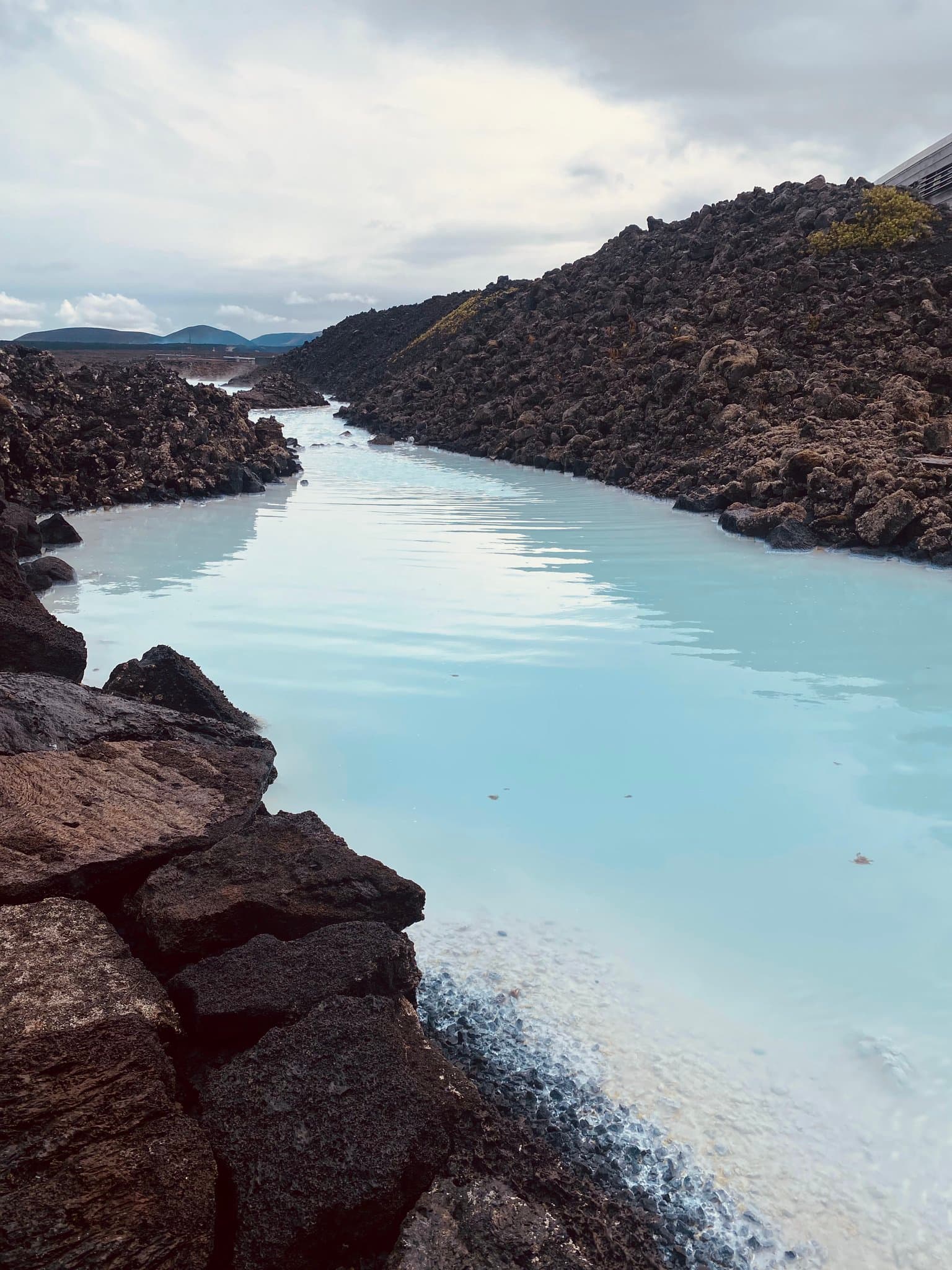 A rugged, hilltop landscape next to clear waterways on a cloudy day.
