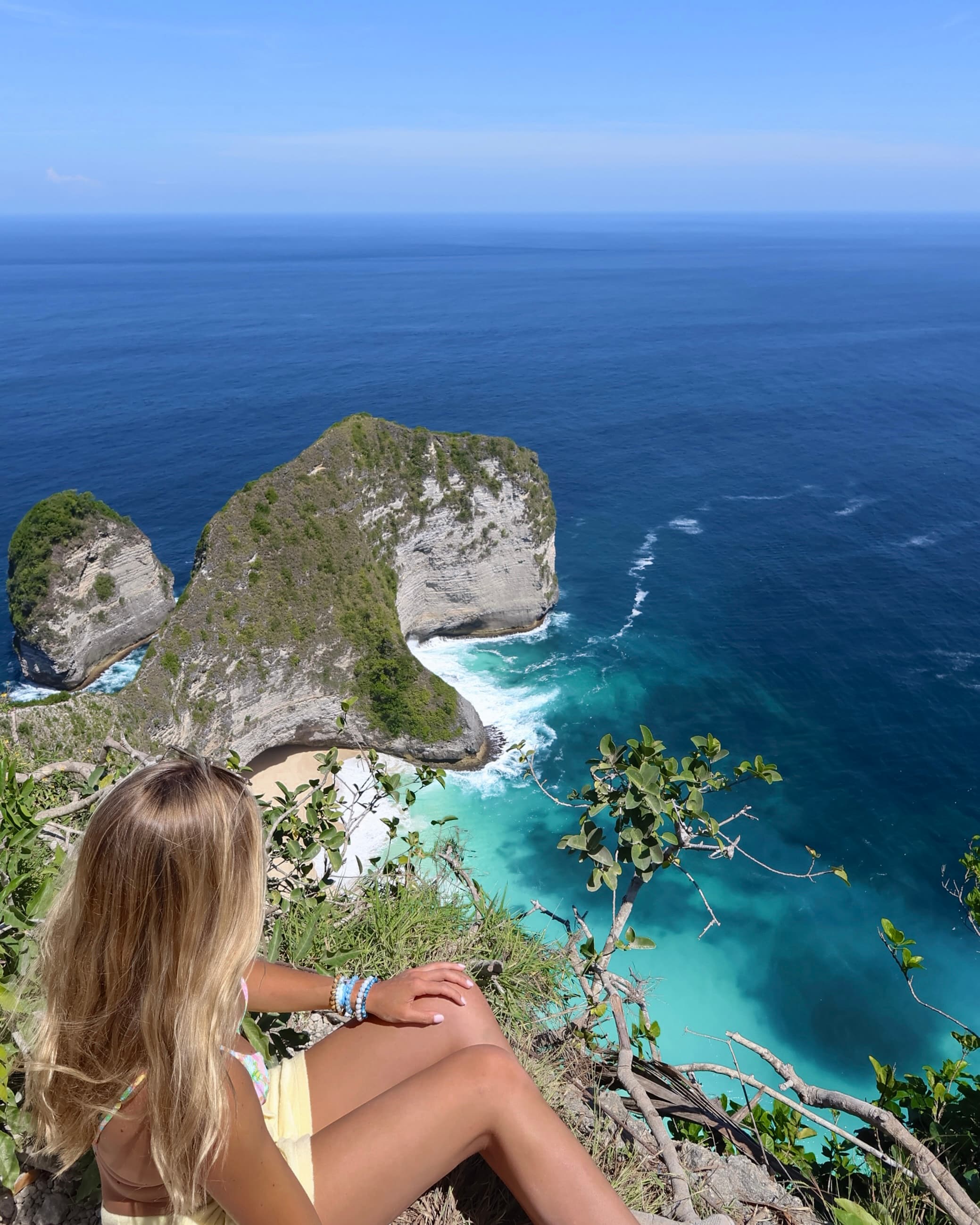 A woman looking out to a view of the sea and coastal cliffs.