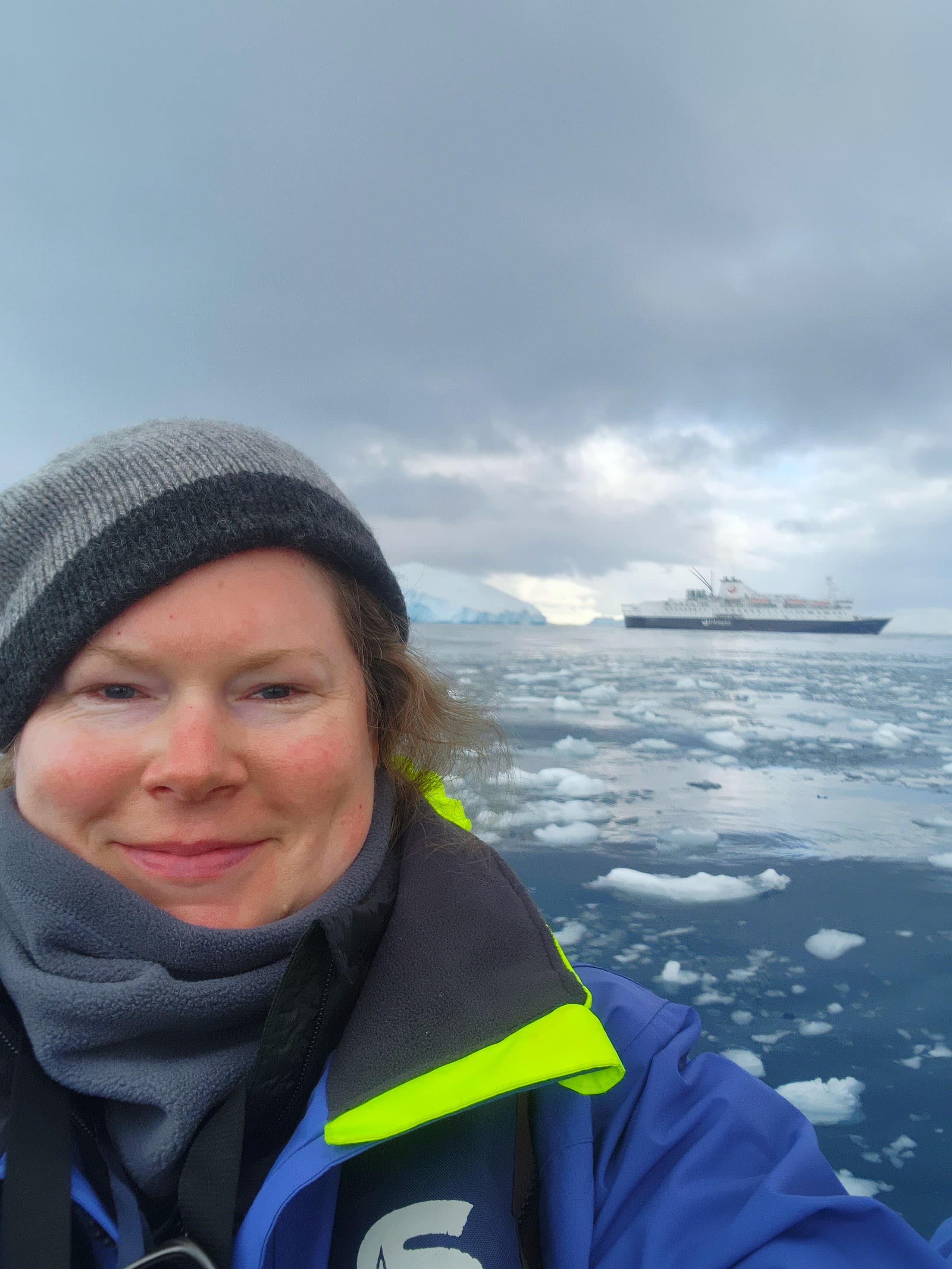 Advisor in a blue winter jacket taking a selfie with an icy Antarctica landscape
