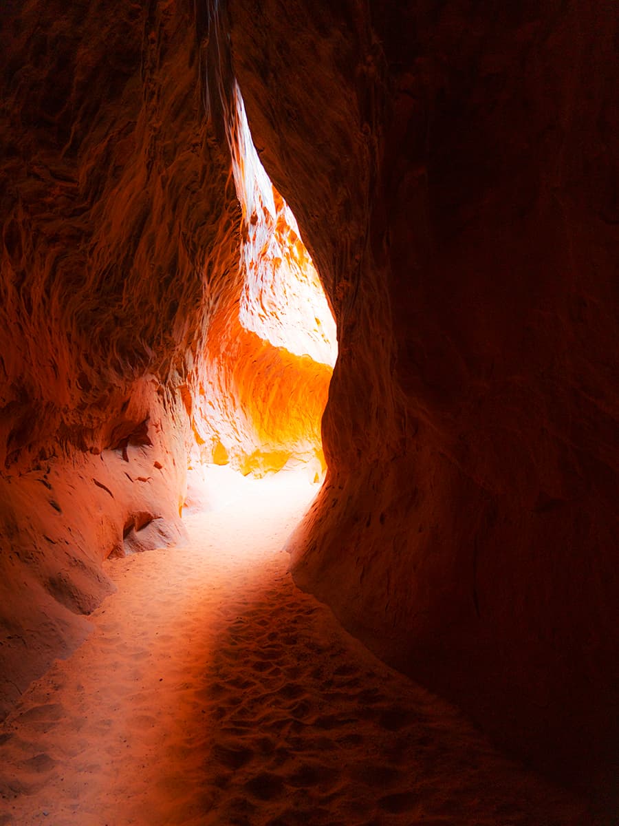 View of light coming through a crevice in a red rock canyon