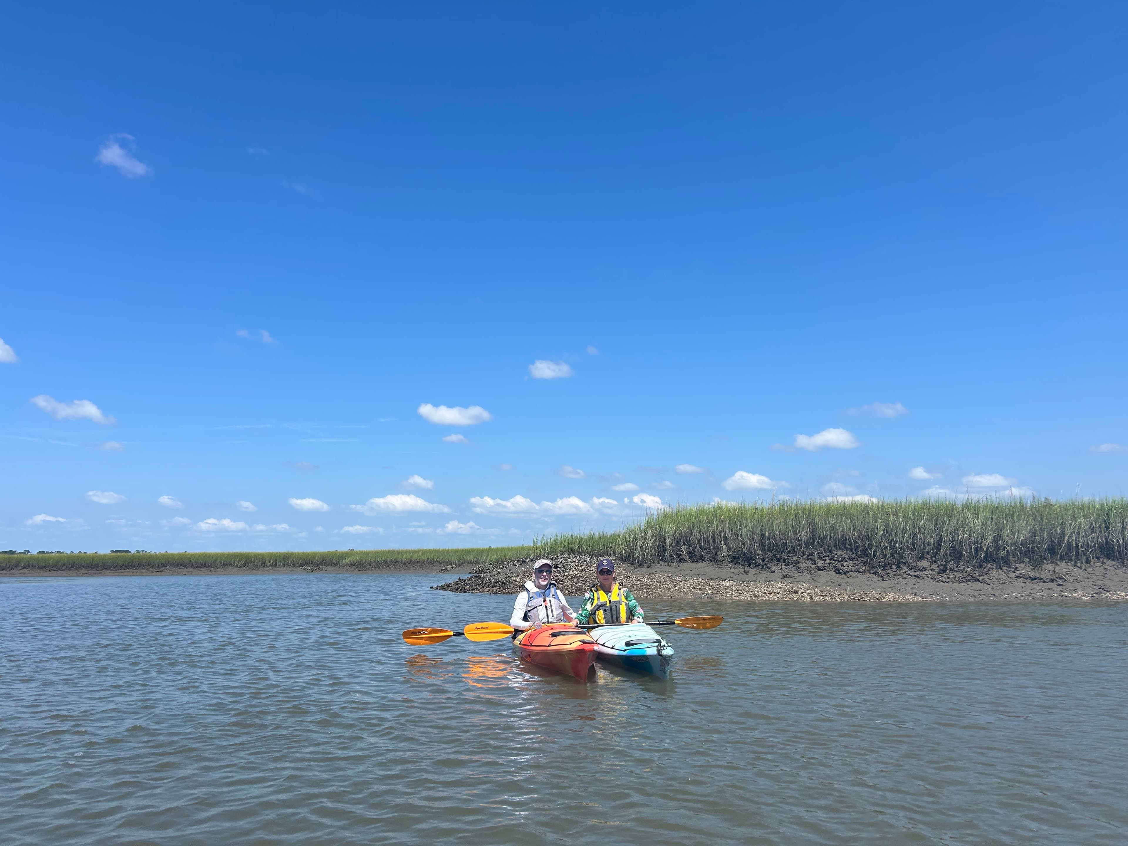 Two people on a river in brightly colored kayaks.
