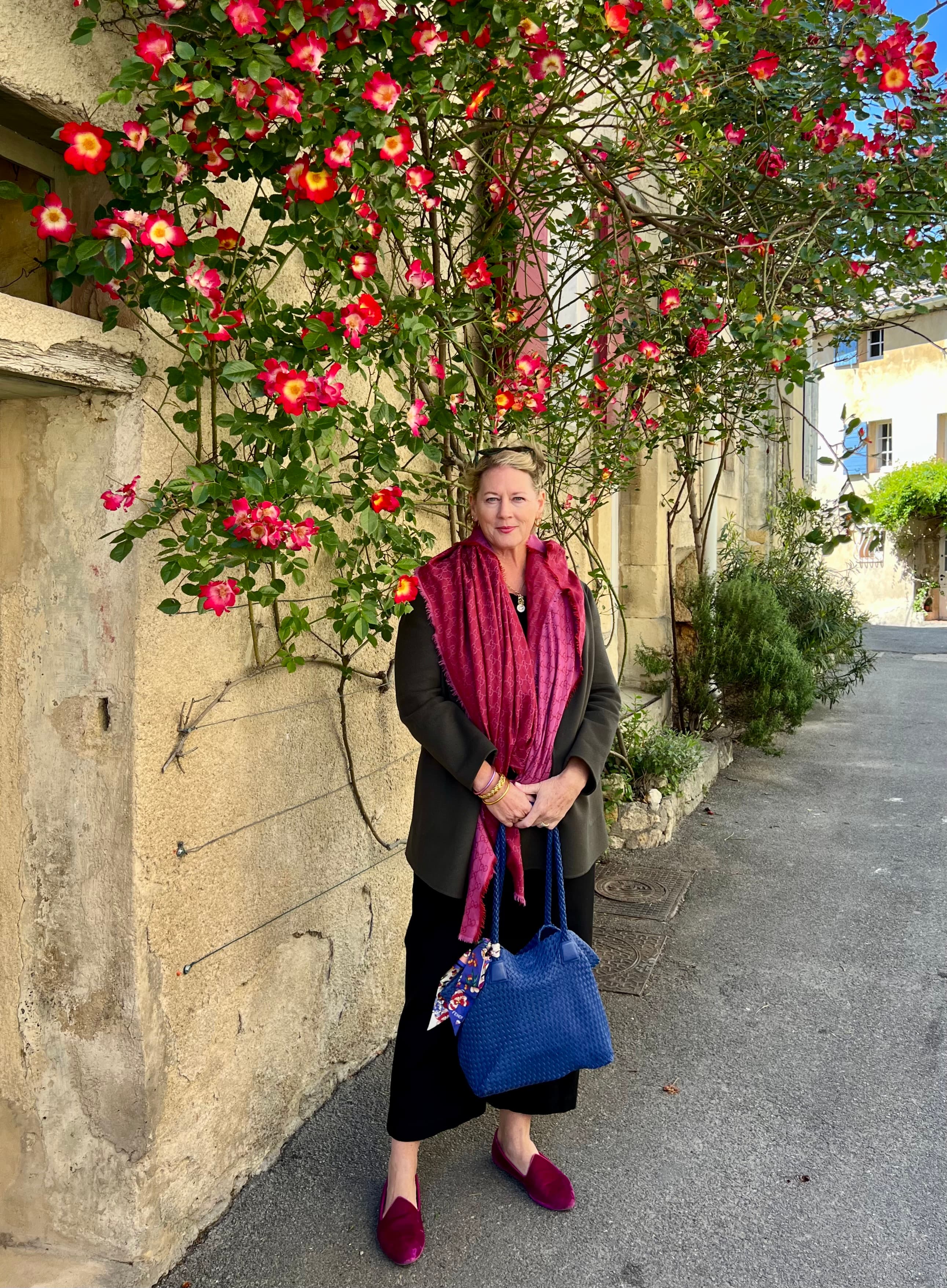 Advisor stands holding a blue tote bag underneath a flowering tree.