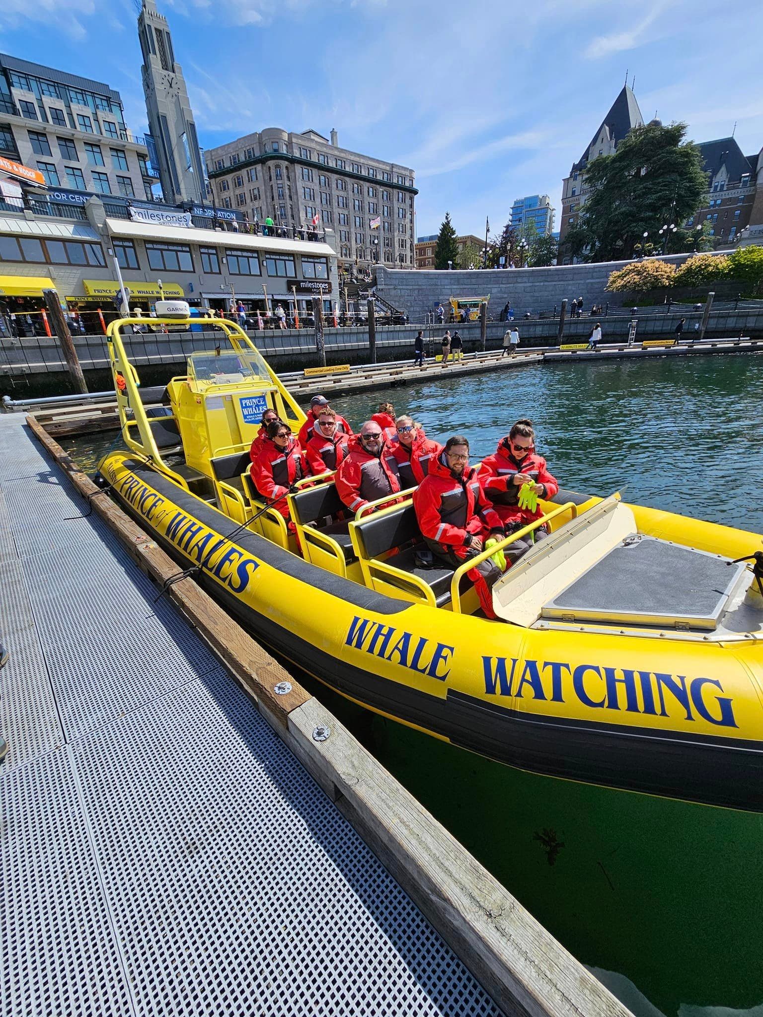 Advisor in a group of people on a yellow whale watching boat docked in a city port