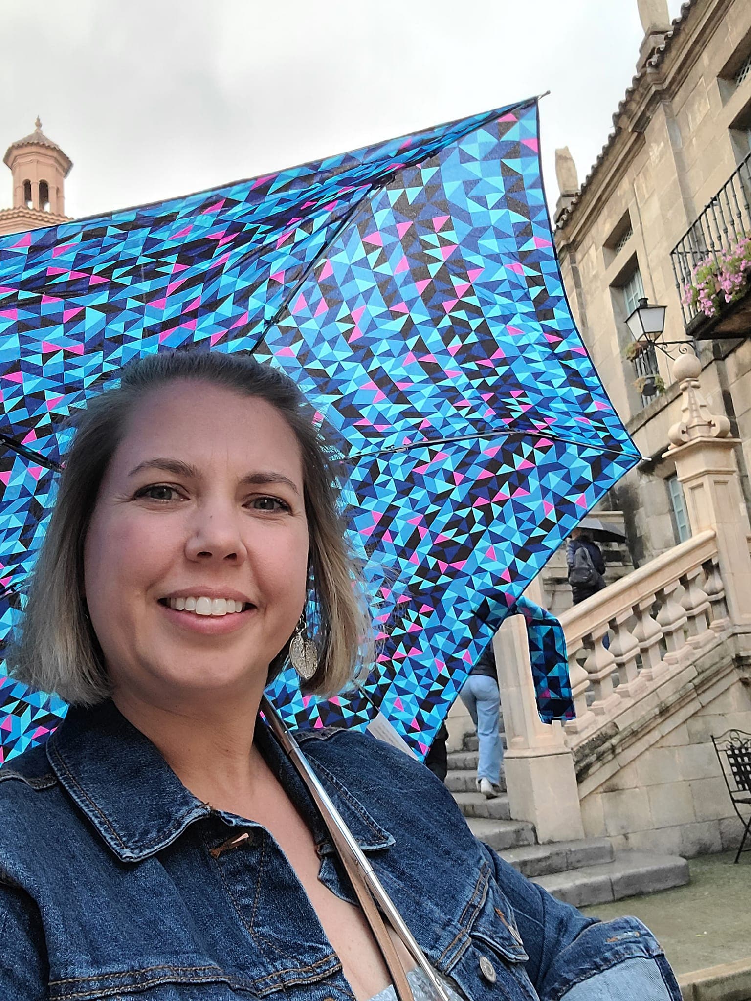 Advisor in a denim jacket holding a blue umbrella on a rainy day