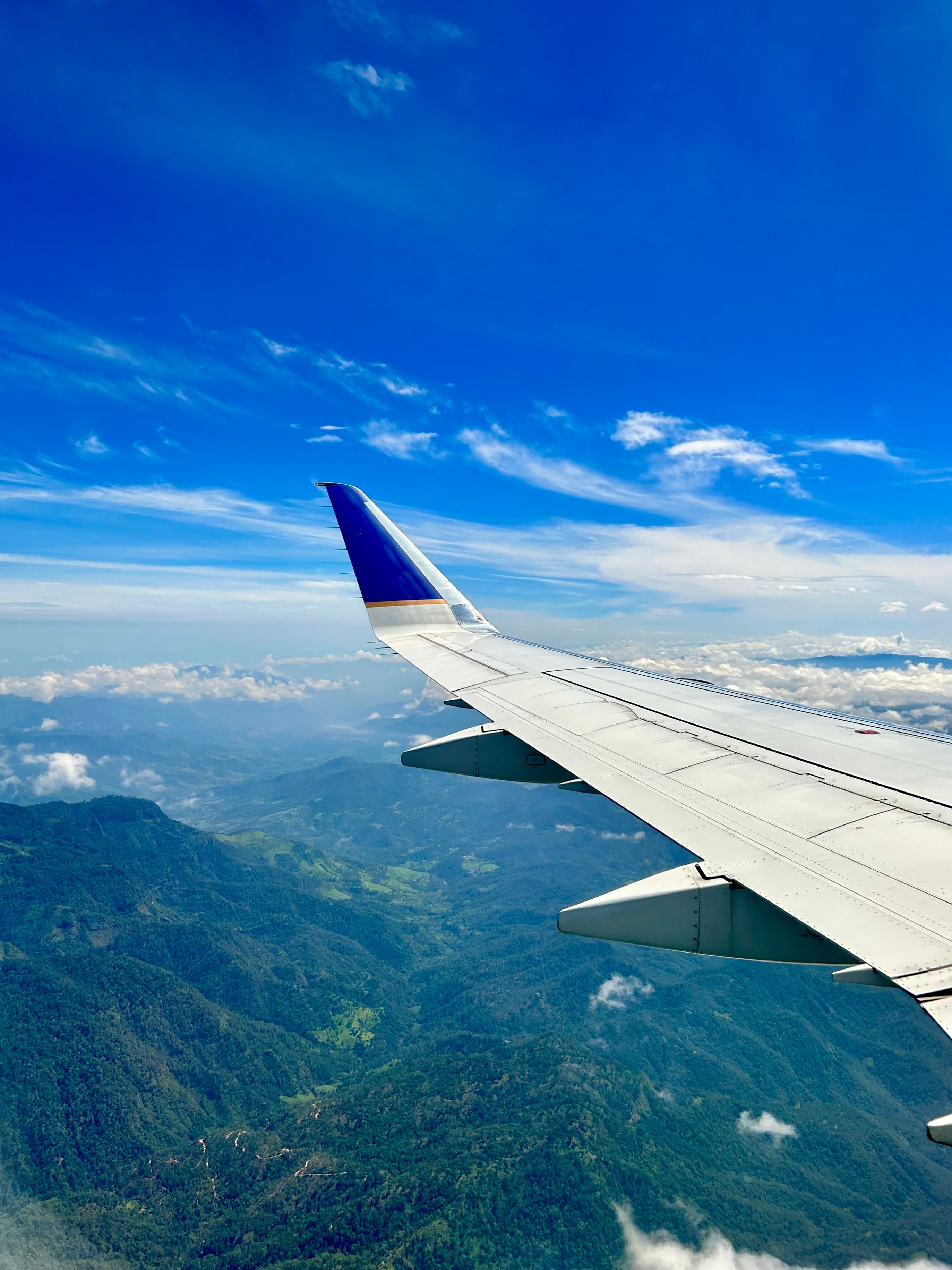 The wing of a plane in the sky taken from inside an airplane.