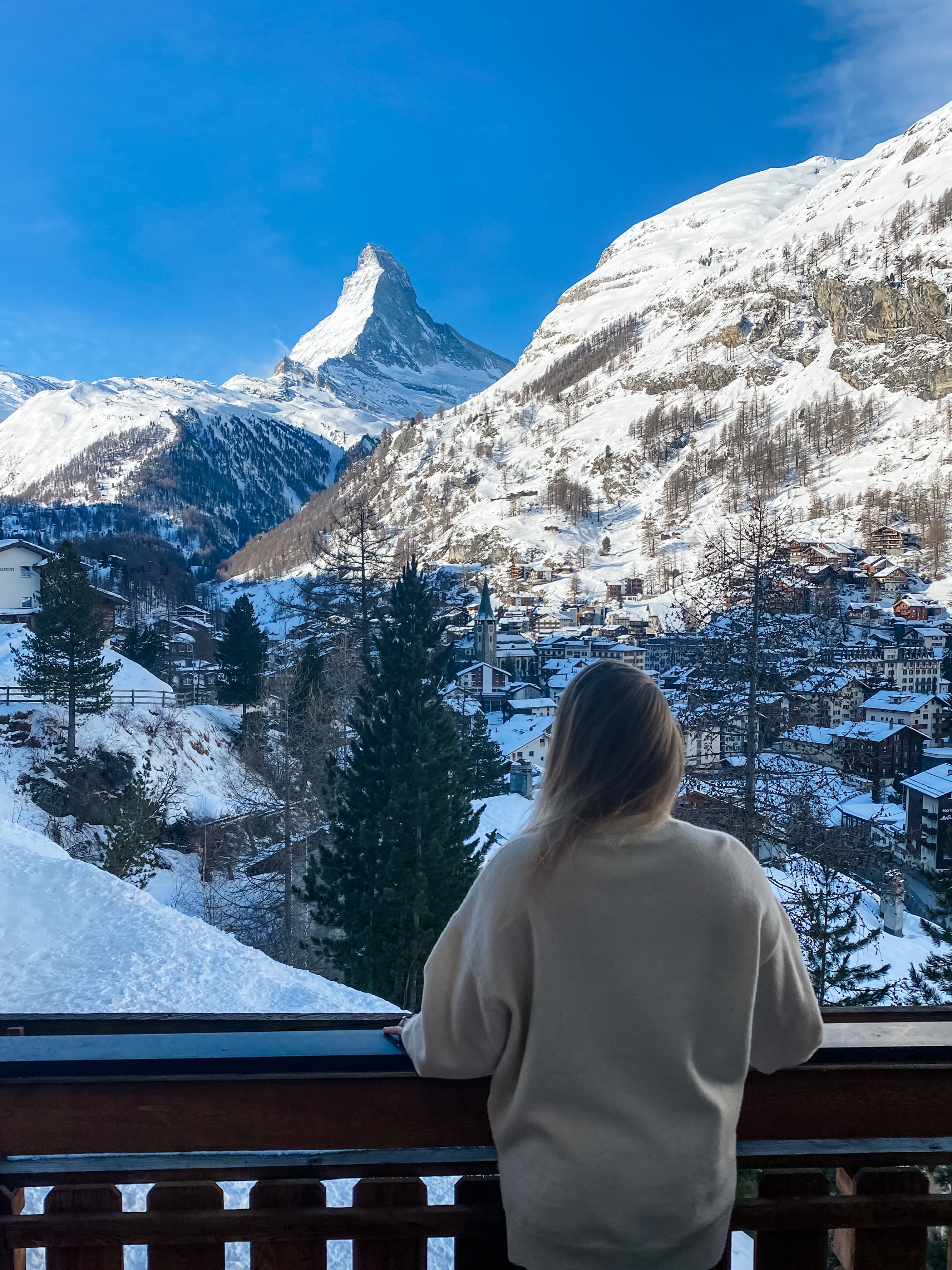 Advisor on a balcony overlooking a beautiful snowy mountain landscape on a sunny day