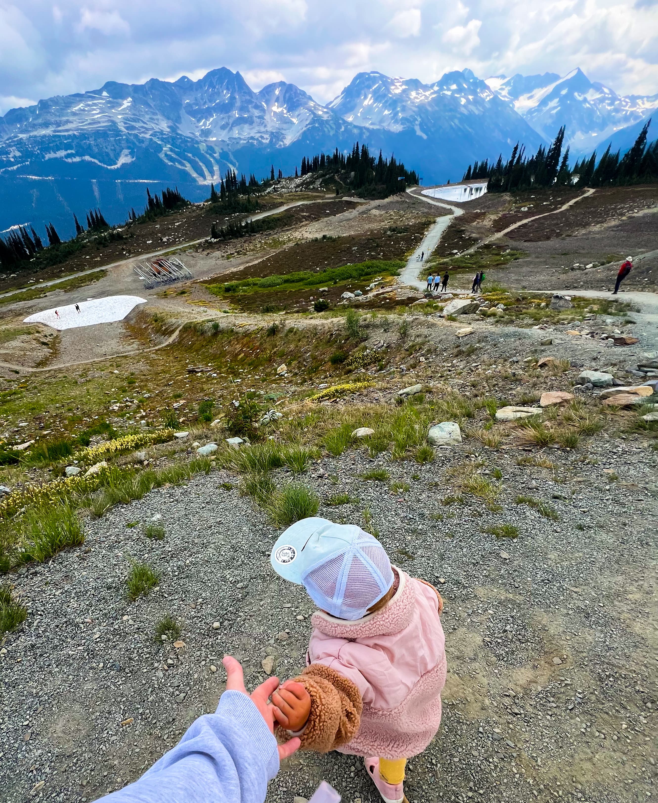 View of a small child holding the advisor’s hand while on a walk through a beautiful mountain landscape